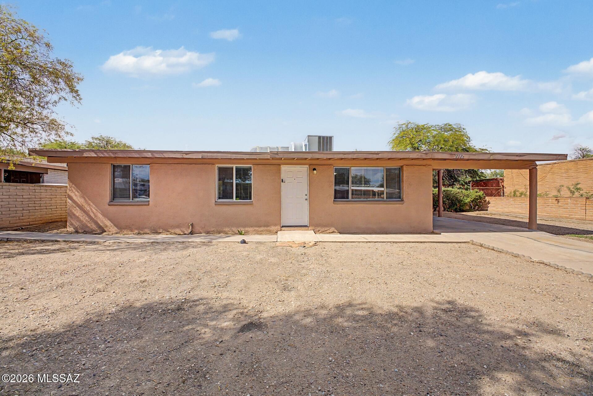 This well-maintained Tucson home offers a functional layout with bright, neutral interiors and flexible living spaces. The kitchen features granite countertops, abundant cabinetry, generous prep space, and a breakfast bar that opens to the adjoining living area. Tile flooring flows through the main living spaces, with wood-look flooring in the bedrooms. Outside, enjoy a spacious backyard with room for entertaining, gardening, pets, or future improvements. A covered patio, covered parking, mature desert vegetation, and a detached storage/workshop building add extra functionality. A great opportunity with plenty of space to make it your own.