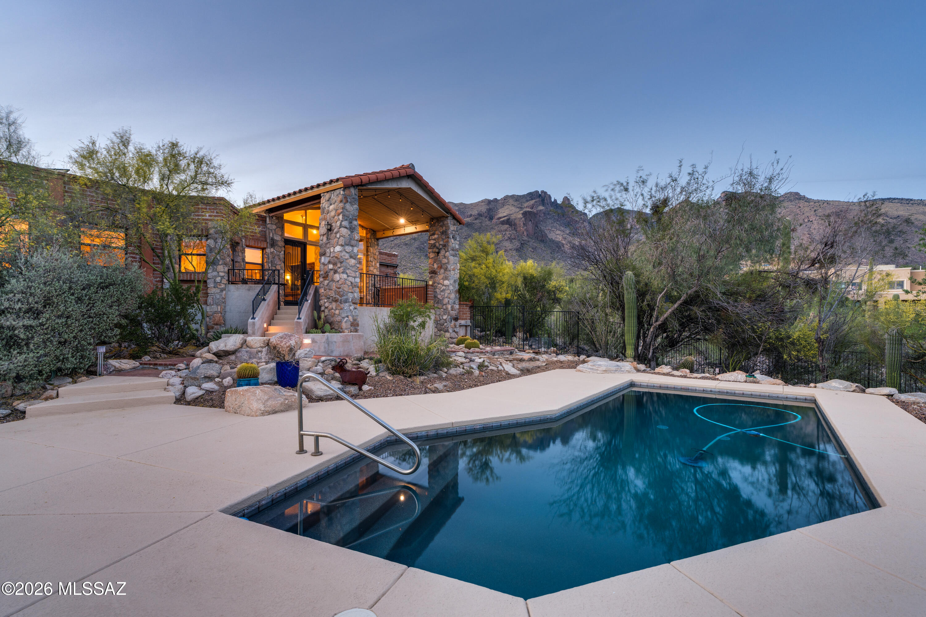 Have you ever dreamed of living high above the city lights - surrounded by a cactus forest, breathtaking mountain vistas, and the serenity of the desert - yet still close to every city convenience? Sometimes dreams really do come true! From the moment you arrive at the community gate, you'll know you've discovered a hidden gem. Follow the scenic drive upward, taking in the sweeping views, until you reach your new home. This meticulously maintained sanctuary sits on 0.81 acre of pristine desert landscape, nestled among majestic saguaro cacti and mature mesquite and palo verde trees, all within the highly acclaimed Catalina Foothills School District. From the L-shaped front courtyard, enjoy stunning views of the Santa Catalina Mountains before stepping into a thoughtfully designed luxury retreat. The solid burnt adobe construction provides excellent insulation and the timeless "Old Pueblo" aesthetic. Inside, classic character blends seamlessly with tasteful modern upgrades. The family room - featuring picture windows perfect for observing mountains, lush vegetation, and local wildlife - offers
exposed wooden beams, a natural stone fireplace, custom window
treatments (motorized shades), and built in Bose speaker system that create a warm, sophisticated atmosphere ideal for relaxation and intimate gatherings. The living room, dining room, and kitchen impress with Spanish limestone flooring, a cathedral ceiling, and a dramatic floor-to-ceiling wall of windows showcasing spectacular saguaro and valley views by day and sparkling city lights at night. The spacious kitchen is ideal for cooking and entertaining, with granite countertops and backsplash, a large central island, breakfast bar, solid wood cabinetry, newer GE Profile stainless steel appliances, and an electric cooktop. The expansive primary suite includes a
private bathroom with custom stonework in the bath/shower area, a dual-sink granite vanity, a jetted tub, and a custom walk-in closet. A cozy reading nook completes the retreat. All bedrooms offer mountain and/or city views and feature new, high-quality carpet installed in March of this year. The comfortable hall bathroom includes a dual-sink granite vanity and a walk-in shower. The laundry room provides abundant solid wood cabinetry, a stainless steel sink framed by granite countertop, and newer GE washer and dryer. Step outside to an enormous covered patio with unbelievable mountain
and city views. Enjoy long evenings on one of several patios, dine by the fountain, relax in the sparkling PebbleTec pool, or simply unwind in the private, quiet backyard oasis surrounded by nature. The pool deck was recoated and the pool pump rebuilt in March 2026. In the same month the 2-car attached garage was upgraded with a new door opener. A newer (built in 2024) detached oversized garage with a workbench/hobby room offers ample space for all your toys. The owned solar system installed in 2023 covers nearly 100% of the property's electricity needs and still has 22 years of warranty left.
Natural gas is available in the street. Be sure to review the full list of property improvements available in the Documents section of the listing. Living in this scenic oasis feels like a permanent vacation - yet you're just minutes from shopping, dining, entertainment, the University of Arizona, Banner University Medical Center, and downtown. Don't miss your chance to own this private piece of paradise!