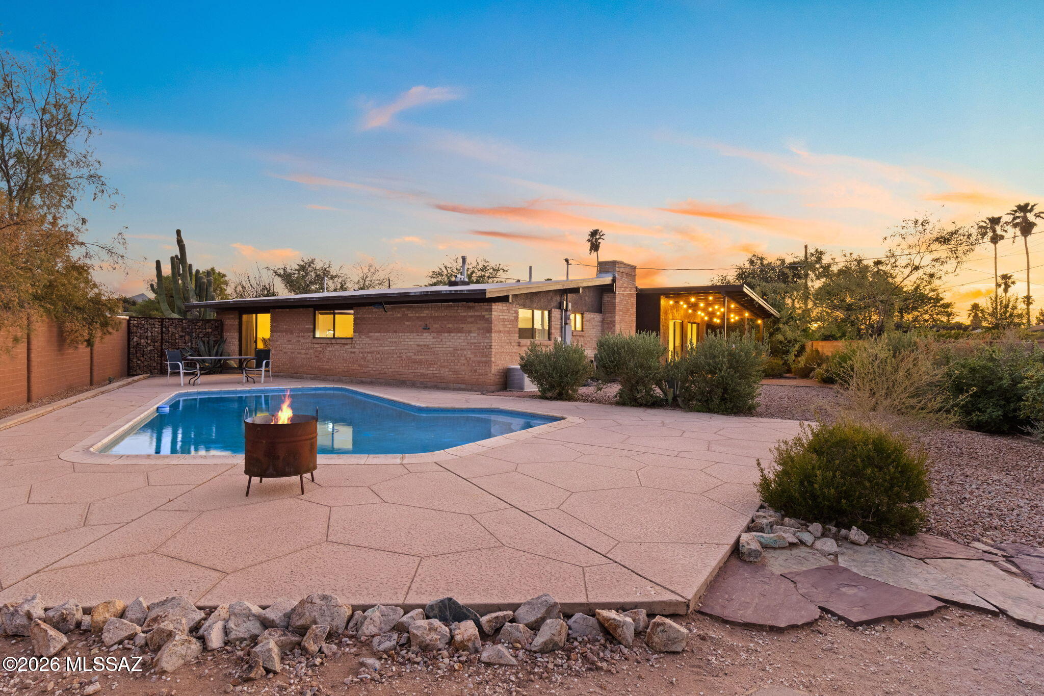 This beautifully remodeled, 3-bed, 2-bath double wire-brick home blends classic architectural charm with modern luxury. The covered front patio invites you to sit back & watch the evening sunset, while the fully landscaped grounds set a picturesque scene. Inside, you are greeted by vaulted ceilings, a bright, open floor plan that has been thoughtfully updated from the studs up. Solid tile flooring flows seamlessly throughout, leading you to an updated kitchen complete with stainless-steel appliances, a dedicated beverage fridge, & breakfast bar. Cozy up in the versatile family/dining room featuring an inviting fireplace. Oversized laundry room serves as climate-controlled flex space easily adaptable into home office/gym. North-facing backyard has fruit trees & shows off mountain views. & desert plantings, a built-in BBQ station, & a massive side yard centered around a sparkling swimming pool. This home truly has it all & is waiting for you to experience it in person