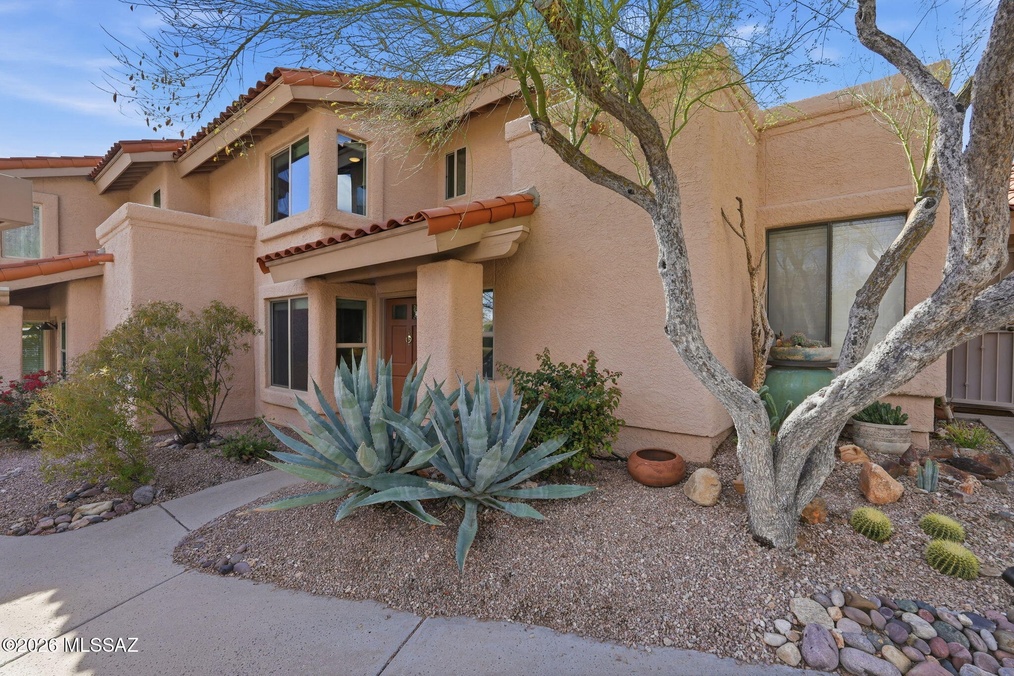 Spectacular 1,370 SqFt two-story Villa in guard gated Rancho Sin Vacas is ideally situated near La Encantada Mall offering upscale shopping & dining in the Catalina Foothills. Set back against the mountain offering resort style amenities, you and your guests will enjoy dual en suite bedrooms, an open concept floor plan with soaring ceilings, dramatic stacked-stone woodburning fireplace, ceramic plank tile on main level, cascading light fixture plus a sleek, updated kitchen. Both bedrooms feature custom walk-in closets and updated baths with dual-sink floating vanities, undercabinet lighting plus large mirrors with accent lighting. Carpeted, wrought iron banister staircase flows to upper landing with carpeted bedroom and den/office. Relax on the private, tiled rear patio with shady pergola and mature shade trees. Neighborhood amenities include athletic & exercise facilities, pool, spa and clubhouse. HOA fee includes water, trash, building exterior, Rural Metro and gatehouse. Water heater replaced 1 year ago. Roof and heat pump replaced 3 years ago. Perfect for part-time or year-round enjoyment!