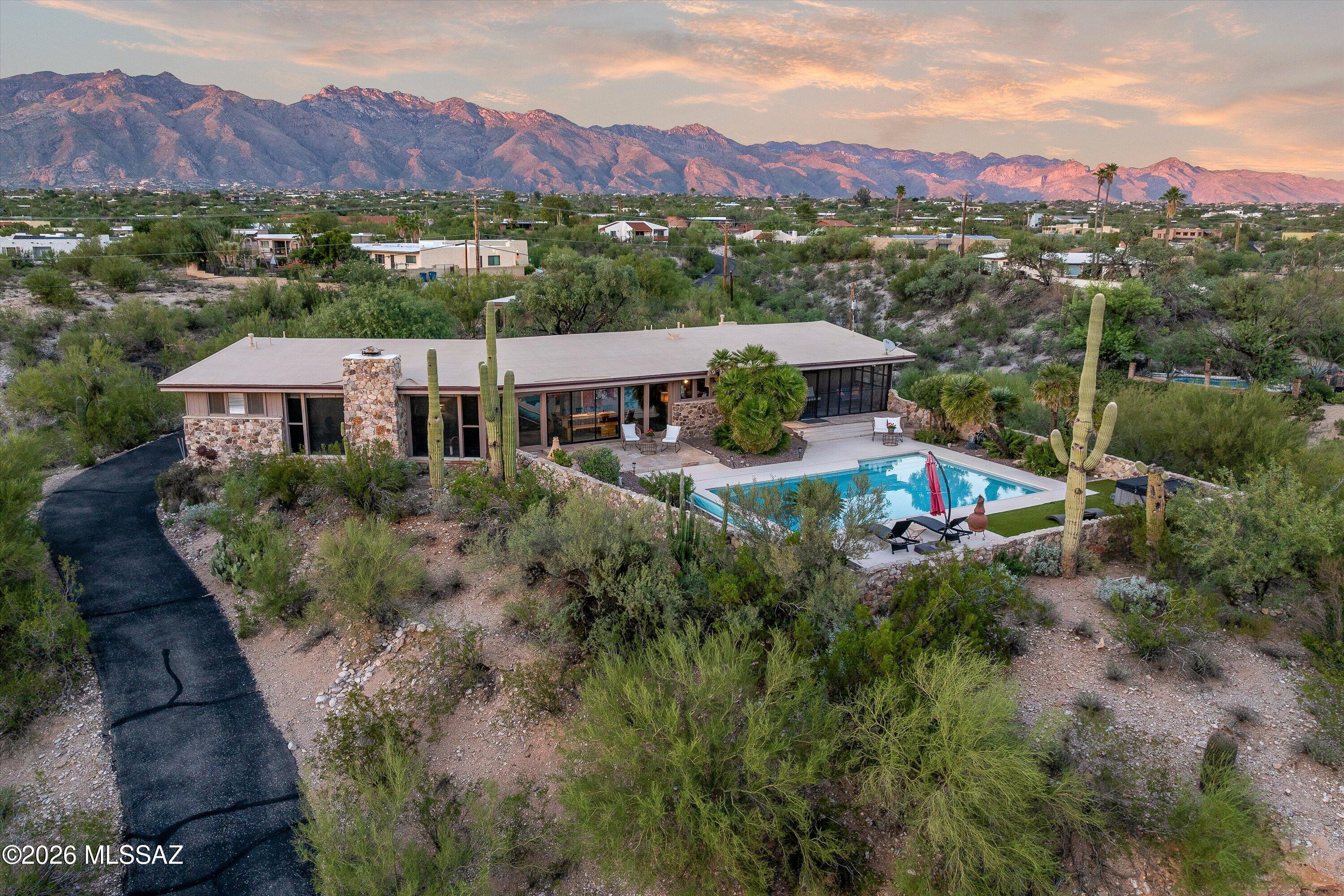 Rare 3+ acre hilltop retreat in the Catalina Foothills. Breathtaking mountain, city-light & sunset views! Mid-century character shines through walls of windows, spacious living/dining & fireplace. Updated kitchen features quartz counters, granite island & cherry cabinetry. 4BR 2½ BA. Primary suite offers dual closets & walk-in shower. An enclosed Arizona Room/Screened In Patio overlooks the sparkling pool, hot tub, flagstone patio & mature landscaping--ideal for indoor-outdoor living. Horses permitted. 2-car garage with workshop & pool bath plus truck-sized carport/storage. $100K+ in documented updates & upkeep, incl. 2 Lennox HVAC systems (2023). Voluntary HOA Fee/ CC& Mandory CCRs apply. Near hiking, biking, dining, shopping. See 3D Video Floor Plan, lifestyle brochure/Map & Upgrade Lis