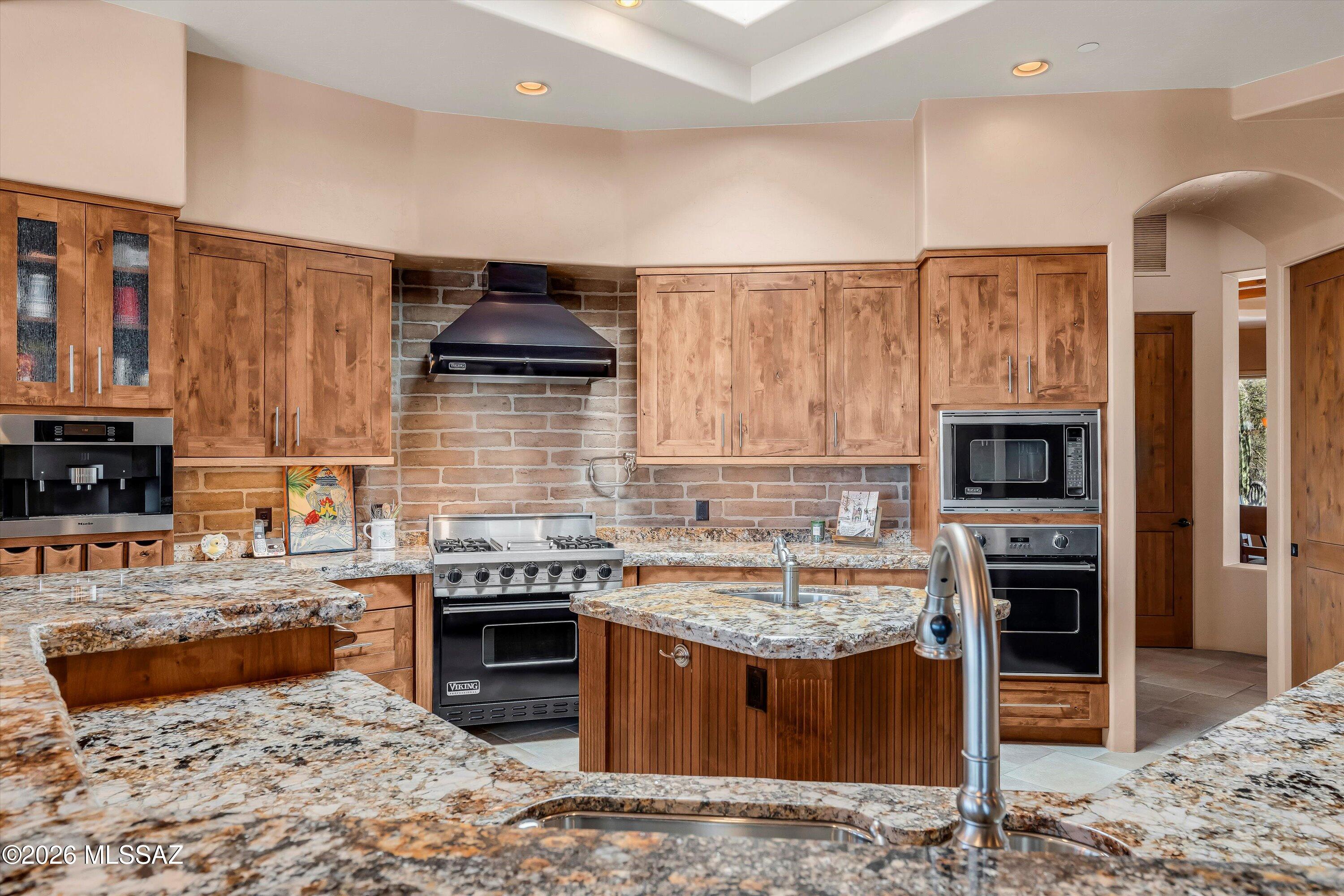 A true desert estate where architecture, artistry, and lifestyle merge seamlessly. Tucked within the gated enclave of Sonoran Preserve on the Bajada near Dove Mountain, this custom Southwest Contemporary residence showcases timeless design, exceptional craftsmanship, and the effortless elegance expected in a luxury desert retreat. Offered fully furnished, this home presents a rare turnkey opportunity, allowing for an immediate and seamless transition into refined desert living. 
A gated entry and circular paver drive create an unforgettable arrival, leading into a private front courtyard complete with a tranquil water feature, offering a peaceful outdoor setting to enjoy morning coffee while taking in desert sunrises and mountain views. Designed with a flowing split-bedroom plan, the home balances privacy with open-concept living, centered around a dramatic great room that serves as the heart of the residence. Expansive windows and organic architectural lines invite natural light throughout while framing serene desert and mountain views, creating a seamless connection between indoor and outdoor living. Throughout the residence, artisan textures, exposed wood beams, curved masonry and brick elements, and thoughtfully curated design details reflect a level of craftsmanship rarely found, creating warmth, character, and timeless desert elegance. A centrally located powder room showcases a striking curved brick feature wall and artisan finishes, further emphasizing the home's custom architectural character.
The chef's kitchen anchors the living spaces with professional-grade appliances, custom alder cabinetry, generous prep areas, and natural gathering spaces that open easily to both casual and formal dining areas. Premium appliance features include a built-in coffee system, professional gas range, and thoughtfully integrated design details that blend beauty with function. A beautifully positioned breakfast nook surrounded by windows captures the beauty of the desert landscape, while the formal dining room showcases rich architectural detail, warm wood accents, and custom finishes that enhance the home's distinctive character. Every space was intentionally designed to feel both refined and inviting, supporting effortless entertaining and everyday living alike.
The private primary suite is thoughtfully separated from the guest wing, offering a tranquil retreat complete with its own fireplace, sitting area, and direct access to outdoor living spaces. The spa-inspired primary bath delivers a boutique resort feel with a freestanding soaking tub, expansive walk-in shower featuring a ProSun tanning system, custom vanities, designer tile work, and upgraded bidet-style toilet features designed to enhance comfort and convenience.
On the opposite side of the home, guest bedrooms connected by a well-appointed Jack and Jill bath provide comfort and functionality while maintaining privacy for family and visitors, each offering private access to the patio for a seamless connection to outdoor living. An additional full guest bath with a walk-in shower and convenient pool access further enhances the home's thoughtful layout, creating effortless indoor-outdoor convenience for guests and entertaining.
Additional living spaces elevate the home even further, including a dedicated den and entertaining lounge complete with a built-in bar, perfect for relaxing evenings or hosting guests. A spacious laundry and utility area with extensive cabinetry and workspace adds convenience while maintaining the home's cohesive custom aesthetic. Every room reflects intentional design, blending warmth, functionality, and architectural artistry.
Outdoor living is nothing short of exceptional, with multiple covered patios, a built-in outdoor kitchen, and a resort-style pool and spa creating a private sanctuary designed for year-round enjoyment. Mature desert landscaping, natural boulders, and layered outdoor spaces provide privacy and tranquility while allowing effortless entertaining. Elevated desert living continues with a private rooftop patio featuring a built-in fire element and panoramic mountain and city-light views stretching across the Sonoran landscape. From sunrise in the front courtyard to sunsets enjoyed from the backyard and rooftop deck, every outdoor space was designed to embrace the beauty of Arizona living.
Originally featured in the SAHBA Parade of Homes, this residence blends architectural artistry with livable luxury, delivering a rare opportunity to own a true custom desert estate ideally located near the golf, hiking, dining, and resort experiences of Dove Mountain, including The Ritz-Carlton and other high-end amenities, while still offering privacy and serenity within its own desert setting.