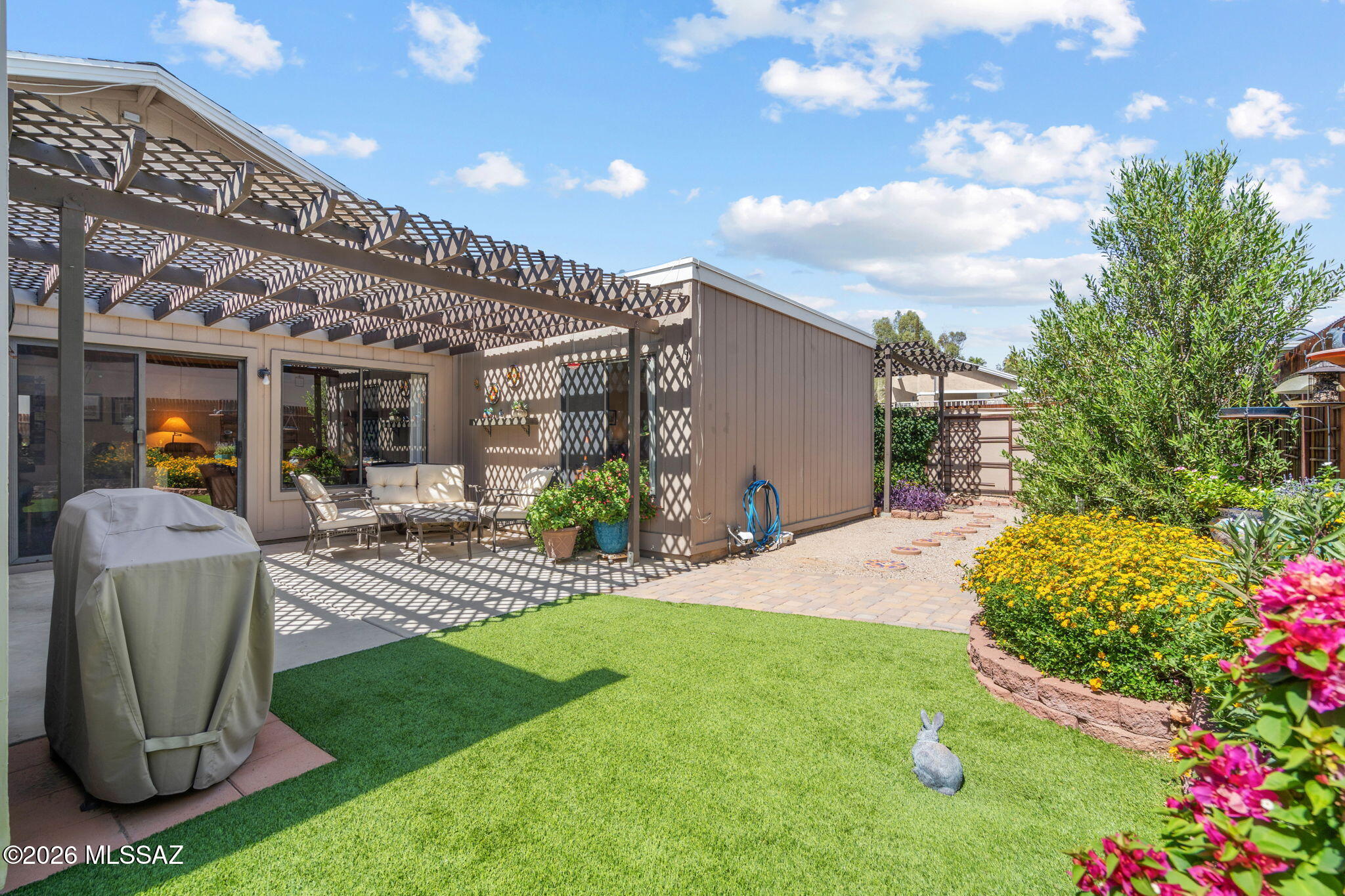 Welcome Home! This one of a kind TH offers a striking first impression with soaring vaulted ceilings and authentic Saltillo tile throughout, creating an open and airy atmosphere. Large living room with FP and plenty of sunlight for that indoor outdoor feel. 2 Large bedrooms with double closets in each. Updated baths, newer AC, and recently coated roof. One of the most standout features of this property is the expansive outdoor space, boasting one of the largest and most meticulously manicured yards in the entire subdivision. This home also includes a two-car garage and access to a community pool and spa for a resort-like lifestyle. Unlike many neighboring communities, this subdivision allows for Airbnb and rental income, making it a unique find for investors or homeowners alike.
