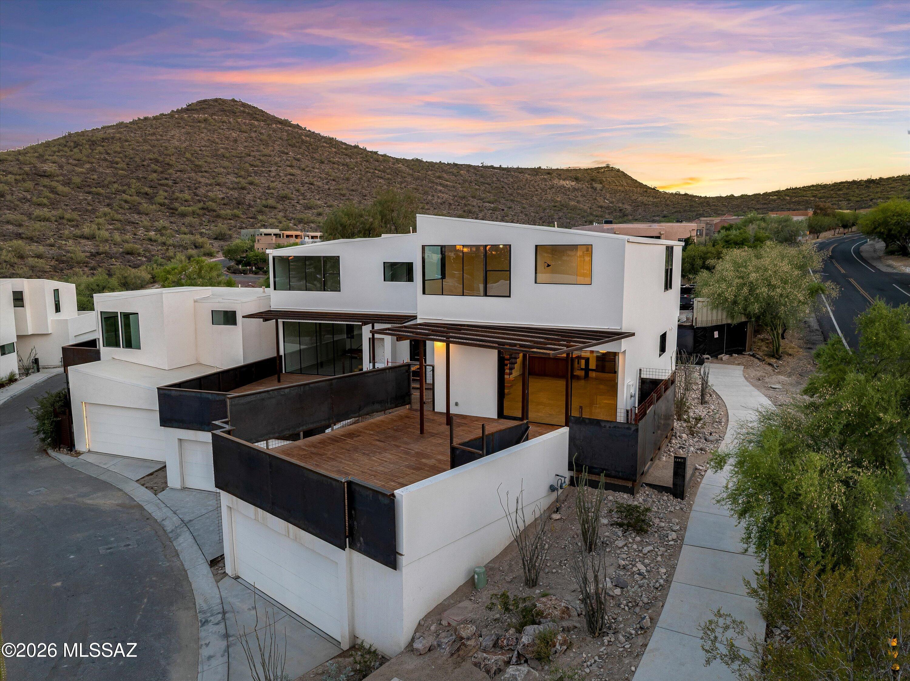 Above the city and beyond ordinary.

Set high on the mountainside, this custom modern home is designed around the views. Floor-to-ceiling glass walls and doors frame the Catalina Mountains, city lights, and stunning Arizona sunsets, bringing the outdoors into every living space. A beautiful teak wood deck with custom metalwork creates the perfect place to relax, entertain, and take in the scenery.

One of only 11 homes in this unique hillside community, the home features modern architecture, clean lines, and thoughtfully selected finishes throughout. For buyers looking for something different, additional floor plans and homesites are also available. Experience a new perspective on Tucson living.