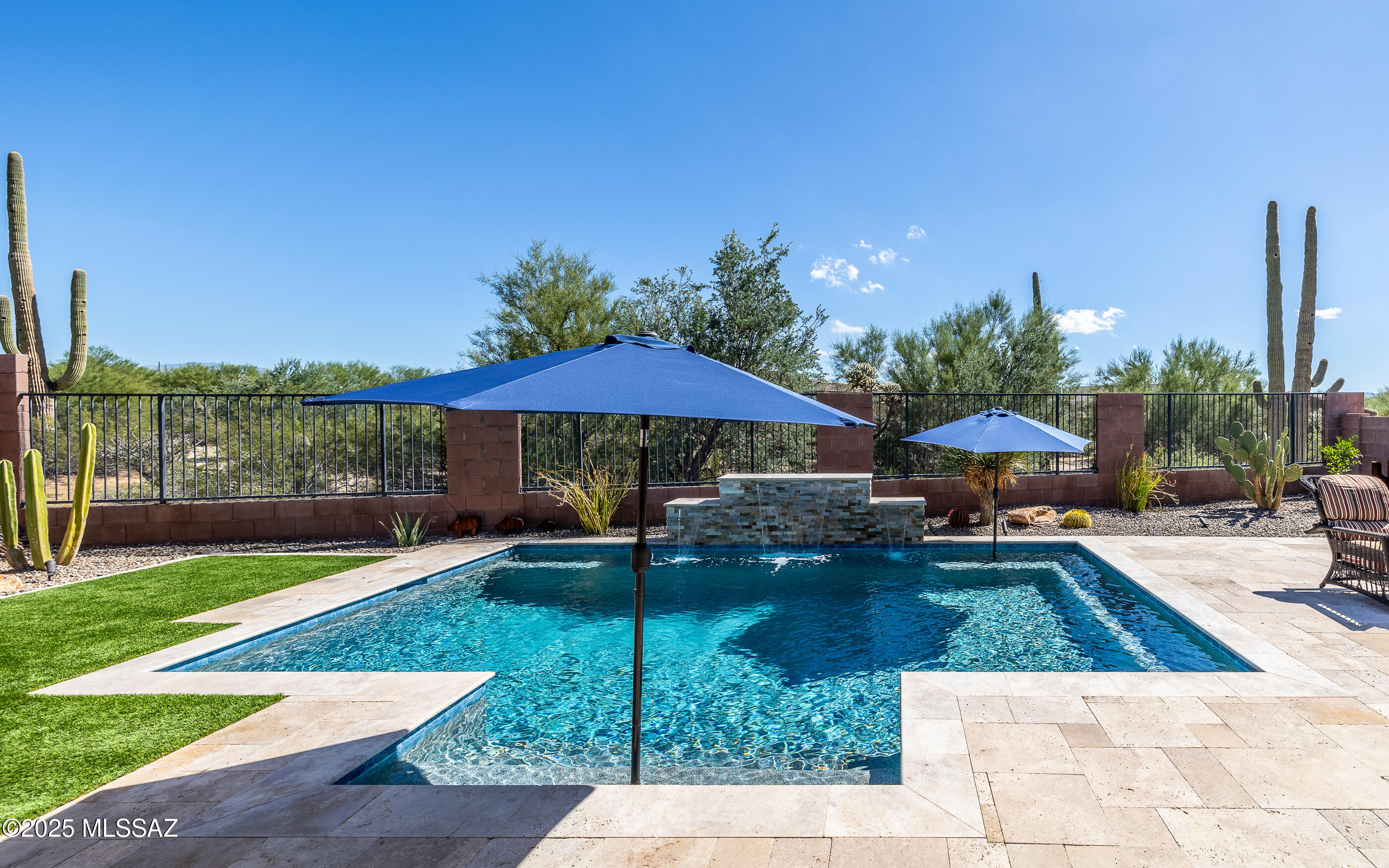 Welcome to resort style living. This residence promises to redefine your concept of luxury living, offering an exquisite blend of comfort and style with an oasis style outdoor paradise and an elegant gourmet kitchen experience. The home showcases bold style in an engaging living design w/plentiful amenities.  Beautiful sparkling pool w/mesmerizing waterfall features, separate bubbling & therapeutic hottub/spa under a private ramada plus abundant patio & porch seating areas. Backing to natural desert habitat w/mountain views and seasonal sunrises are yours to enjoy.  The kitchen is one of the most spectacular designs in Dove Mountain.  Spacious kitchen dining, and if desired a large formal dining room (or billiards room or extra gathering area). Double door den/office, too!  A great home!