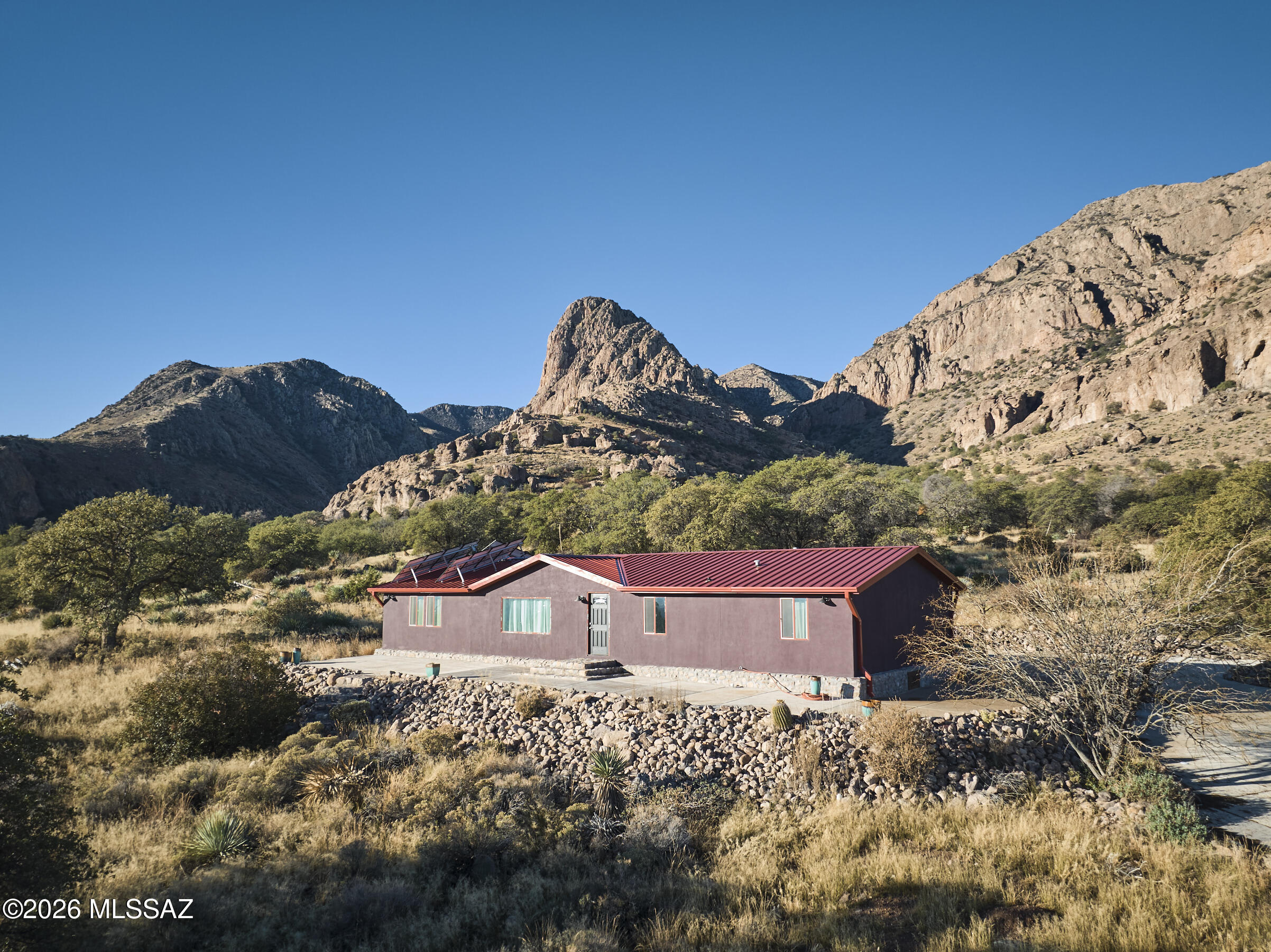 Wow!  What a view! MF Home on 40 acre lot bordering the Chiricahua Wilderness. 100's of huge oaks, meadow, canyon, wildlife, wildflowers, one of the most beautiful land parcels in Portal area with views of Mangus Dome. Magnificent 360Â° views, Peloncillos.  Bortle 1 & 2 dark night skies. Modern interior with updated laminate flooring,granite counters and stainless steel appliances in kitchen, this affixed manufactured home is stucco'd  and features a large porch and extensive rockwork around the home to expand entertaining to the outdoors.  New well, septic, and power to property, back up solar system, propane generator, concrete driveway from property line. Apache granary & ancient petroglyphs in NF adjacent to property. Property is fenced and shipping container may stay with property.