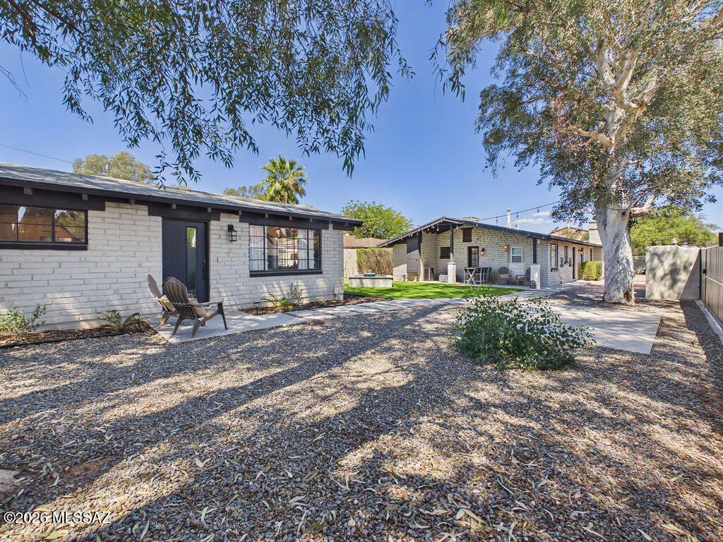 This stunningly reimagined home in Tucson's highly sought-after Blenman-Elm neighborhood is within walking distance of Banner Health and the University of Arizona. This thoughtfully redesigned property blends mid-century character, modern finishes, and income-producing potential--all in one exceptional setting.
 
Step inside to a light-filled open living space featuring soaring wood-beamed ceilings, exposed brick walls, and a cozy fireplace that creates the perfect balance of warmth and style. The seamless flow into the dining area and kitchen makes this home ideal for both entertaining and everyday living. The beautifully updated kitchen is a standout, showcasing quartz countertops, white cabinetry, farmhouse sink, designer backsplash, Reverse Osmosis water, and a full suite of stainless steel LG appliances. The main home offers 3 spacious bedrooms and 2 fully renovated bathrooms, all designed with a clean, modern aesthetic.
 
Adding incredible versatility, the property includes a detached casita/guest house with its own private entrance--complete with a full kitchen, living space, bathroom, and laundry. Perfect for short-term rental, multigenerational living, or guest accommodations.
 
Step outside to your private oasis--an entertainer's dream featuring a low-maintenance turf yard, custom water feature, string lighting for evening ambiance, covered patio for outdoor dining, and mature trees providing shade and privacy. The surrounding perimeter wall, with large sliding gate for private parking access, enhances both privacy and security, creating a peaceful, secluded setting rarely found in central Tucson.
 
This home has been extensively upgraded, including new HVAC (2026 casita) and newer HVAC (2020 main house), water heaters, appliances, and finishes throughout--offering true move-in ready convenience.