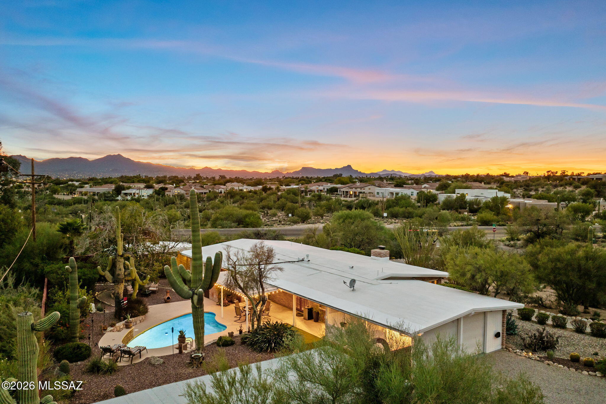 Set on nearly an acre in the Catalina Foothills, this distinctive residence showcases sweeping Catalina Mountain views in a private desert setting. The single-level main home offers 2,000 sq ft with 3 bedrooms, 2 baths, Saltillo tile, a wood-burning fireplace, formal dining room and kitchen with island, breakfast bar and walk-in pantry. A detached 447-sq-ft guest house features 1 bedroom, 1 full bath, a rooftop deck and private driveway, ideal for extended guests or multigenerational living. A pool, covered patios, deck, mature desert landscaping, block walls and RV parking complete the outdoor setting. All within the Catalina Foothills School District, minutes to shopping and dining and under 10 miles to the University of Arizona.