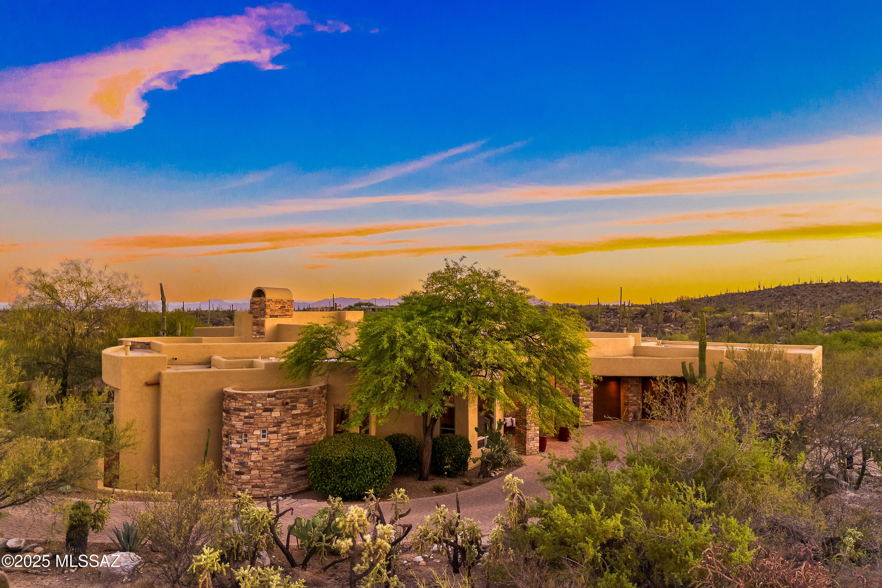 Located in the prestigious guard gated community of The Estates at Honey Bee Ridge, this 4,040sf 4BR/4 ½BA custom soft contemporary home is nestled among dramatic rock outcroppings and towering saguaros, offering breathtaking views of the Catalina Mountains and Pusch Ridge. A paver driveway leads to the home, where elegant, stacked rock finishes set the tone for the refined design within. Thoughtfully crafted with comfort and sophistication in mind, the residence features expansive walls of windows that beautifully frame the surrounding desert landscape. The kitchen showcases rich natural materials, including cherry wood cabinetry, granite countertops & spacious center island w/ 5-burner gas cooktop, stainless appliances, double ovens & casual dining nook highlighted by a curved wall of windows. Each generously sized bedroom includes its own en-suite bathroom, ensuring privacy and comfort for family and guests. 
The great room is centered around a cozy fireplace and wet bar, complete with additional cabinetry and countertops perfect for entertaining. A formal dining room offers a classic setting for special occasions. Luxurious primary suite is a true retreat, featuring a circular alcove entry w/niches romantic fireplace, a large sitting area w/panoramic views, jetted tub, large separate walk-in shower & spacious walk-in closet. Step outside to the resort-style backyard, where you'll find a solar-heated pool and spa with an in-floor cleaning system, a large covered patio, paver and flagstone walkways, a built-in BBQ & gas Kiva fireplace with banco seating all set against professionally landscaped grounds designed for relaxation or entertaining. Oversized 3-car garage has storage cabinets. A  heart-shaped labyrinth is your own private Zen sanctuary; a space to center yourself and reconnect. Walk its winding path as a form of moving meditation or simply rest on the bench and allow yourself to absorb the peaceful energy of the Universe. This prime location offers immediate access to Honey Bee Canyon Park and scenic walking and biking trails, including the Vistoso Trails Nature Preserve with its 6.2-mile, eight-foot-wide concrete path, and The Loopa 138-mile paved trail system that winds through greater Tucson. Outdoor enthusiasts will also enjoy nearby Catalina State Park, ideal for hiking, birding, and horseback riding. Just minutes away, the exclusive Stone Canyon Club features a top 100 ranked golf course, state-of-the-art fitness center, clubhouse amenities, fine dining, and a full calendar of social activities. Membership options include both golf and social packages each offering access to luxury facilities, with golf privileges reserved for golf members. Also close by, the Oro Valley Marketplace offers open-air shopping, diverse dining, a movie theater, and weekend evenings filled with live local music. This is more than just a home; it's a lifestyle. A rare opportunity to own your dream home in one of Oro Valley's most desirable communities, surrounded by breathtaking desert views, natural beauty, and world-class amenities.