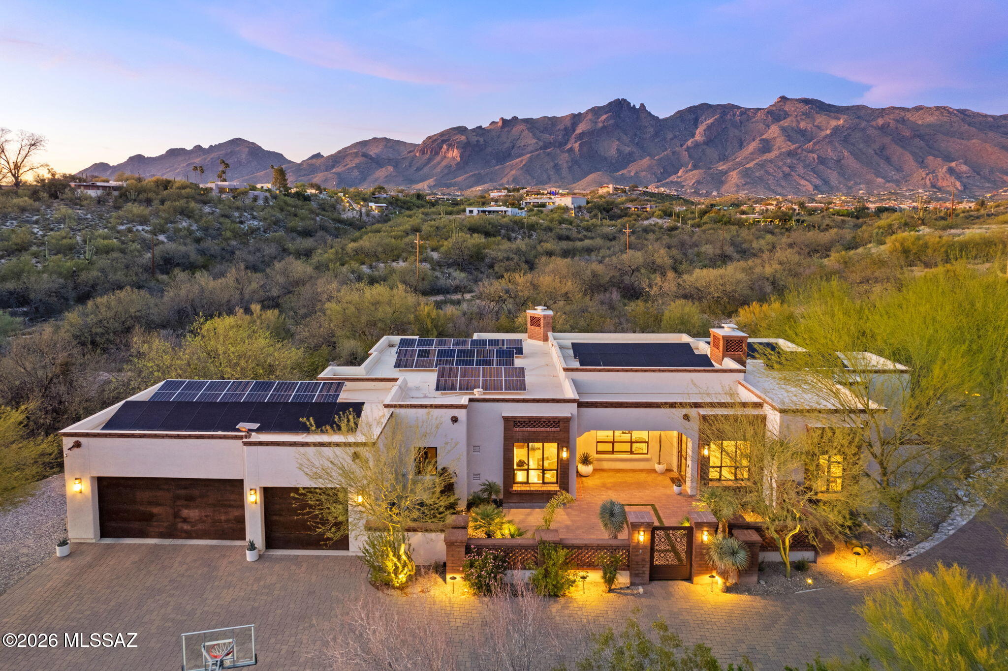 Located in the gated community of Colonia Del Sol in the highly desirable Catalina Foothills, this 2017-built Spanish Colonial style home sits on a spacious, private homesite with stunning mountain views. This home, built by renowned builder Jeff Franks, is within walking distance to Hacienda Del Sol Guest Resort and is located in the Catalina Foothills School District.
Designed for effortless single-level living with no interior steps, the thoughtfully designed 4-bedroom floor plan includes two guest suites with ensuite baths and walk-in closets.
The great room features dramatic beamed ceilings with hand-carved corbels, hand-plastered fireplaces in the dining and living areas, elegant travertine flooring, and floor-to-ceiling steel sash windows that fill the home with natural light. The gourmet kitchen offers top-of-the-line appliances, a large granite island, and a stylish bar area that opens seamlessly to the main living spaces, ideal for everyday living and entertaining.
Outdoor spaces include a welcoming front courtyard, expansive paver driveway with additional parking, refreshed landscaping with exterior lighting, and a private backyard retreat with a PebbleTec saltwater spool with automated cover.
Additional highlights include a 21 kWp owned solar system, newer exterior paint, Hubbardton Forge exterior lighting, reverse osmosis system with instant hot water at the bar, custom wardrobe cabinetry in the primary suite, upgraded carpet, and a 3-car garage with split AC and two EV charging outlets.
Enjoy privacy, energy efficiency, and refined desert living just minutes from premier golf, hiking, shopping, and the best amenities of the Catalina Foothills.