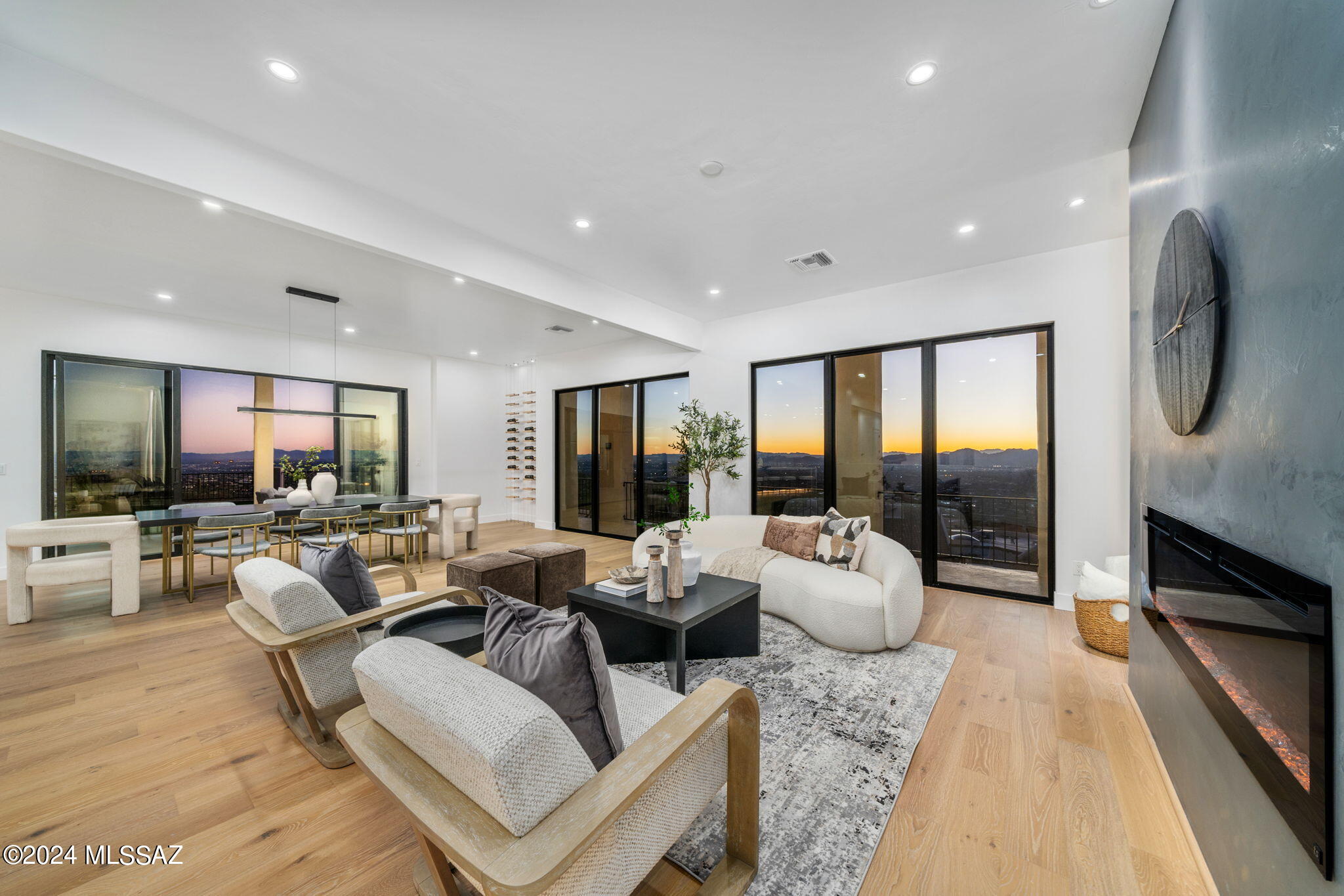 Perched above Skyline Country Club, this 4-bed, 5-bath Synrgy design home offers unmatched Tucson mountain and city views. The grand entrance through an oversized pivot door, unveils an open floorplan seamlessly blending modern design and timeless elegance. Highlights include engineered wood floors, large double-pane windows, spa like primary retreat, gourmet kitchen with 10' gas strut window and 10' ceilings, . The gourmet kitchen opens to a dining area and a private oasis with a pool and stunning views. The primary spa suite features a spacious bedroom, ensuite bathroom with a 13ft shower room, terrazzo stone soaking tub, and backlit mirrors. The walk-in closet is tailored with custom closets. Additional features include a guest suite with its own kitchen, a large laundry room with cus