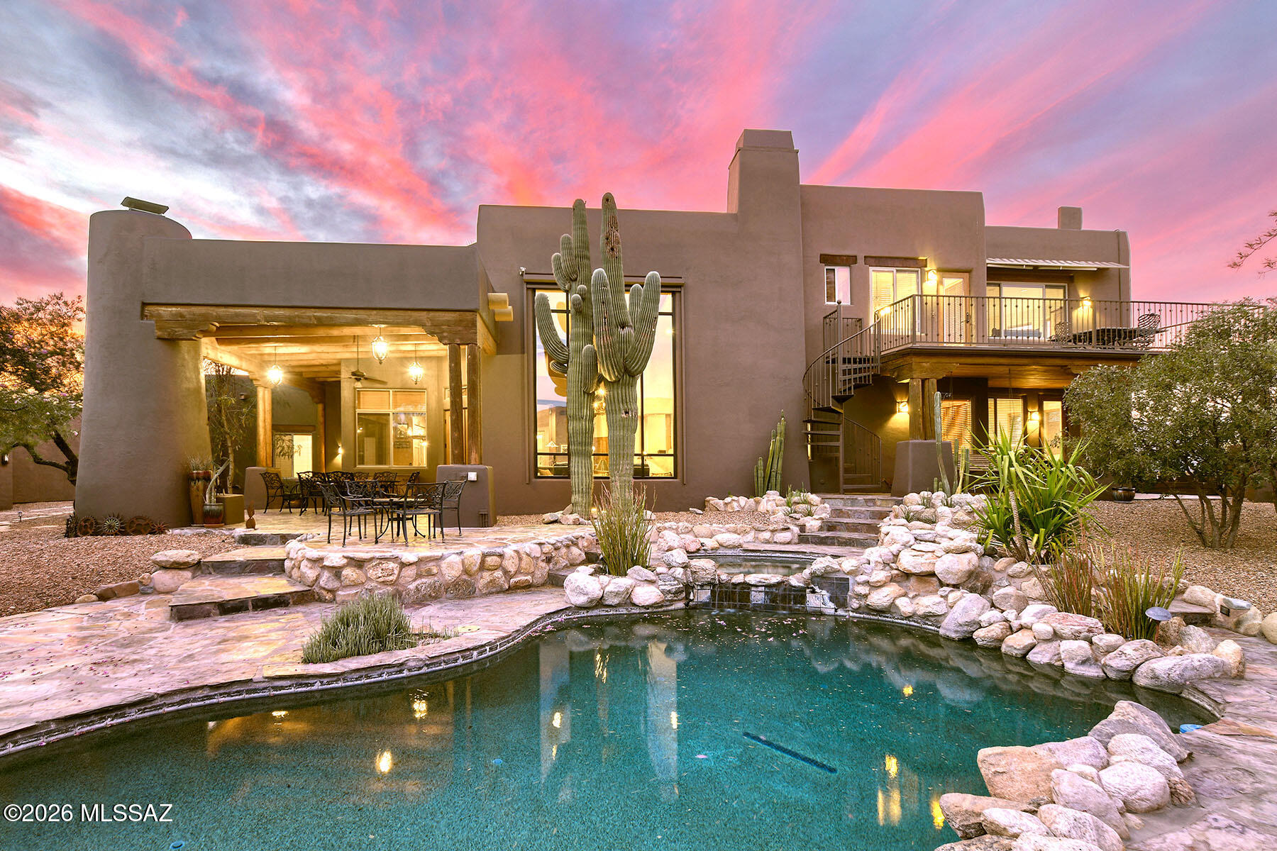 Nestled behind custom gates on over five private acres, this extraordinary equestrian estate is surrounded by sweeping mountain views and the natural beauty of the Sonoran Desert. A long, illuminated driveway welcomes you to a stunning custom Southwest residence and authentic hacienda-style casita, thoughtfully designed to blend luxury living with timeless desert charm. Equestrians will appreciate the exceptional setup featuring a 5-stall barn with tack room, two riding arenas, and convenient access to the scenic trails of Saguaro National Park East. Inside, the dramatic great room showcases soaring 24-foot ceilings, rich flooring, exposed beams, a striking slate fireplace, and walls of glass framing spectacular saguaros and mountain views. The updated chef's kitchen is truly the heart of the home featuring granite counters, hand-rubbed maple cabinetry, large center island, 6-burner cooktop, double ovens, Dacor warming drawer, walk-in pantry, casual dining, and bar seating. The luxurious main-level Primary Suite offers its own fireplace, cozy window seat, spa-inspired remodeled bath with standalone soaking tub wrapped in stacked stone, dual granite vanities, designer shower, concrete flooring, two walk-in closets, and private access to the patio and hot tub. The main level also includes additional bedrooms, laundry room, and oversized 3-car garage with newly coated flooring. Upstairs, a private guest retreat which is perfect for multi-generational living features a separate living area, bedroom, bath with teak wood flooring, and dining room that opens to a balcony perfectly positioned for stunning mountain views and moonrises. Outdoor living is equally impressive with a covered patio featuring wood plank ceilings, fireplace, outdoor kitchen and BBQ area, resort-style pool and spa, and expansive yard spaces. Equestrian amenities include a fully functioning 5-stall barn with tack room, two arenas, covered RV parking, hay barn, separate exercise room, and a 700-square-foot workshop with full bath. The detached hacienda-style casita offers incredible privacy for guests with authentic architectural touches, including a welcoming wood door imported from India, and its own private yard. This home is truly an exceptional desert sanctuary offering luxury living, privacy, and premier equestrian facilities in an unforgettable setting. Adjoining 4.21 acres to the east is available for sale.