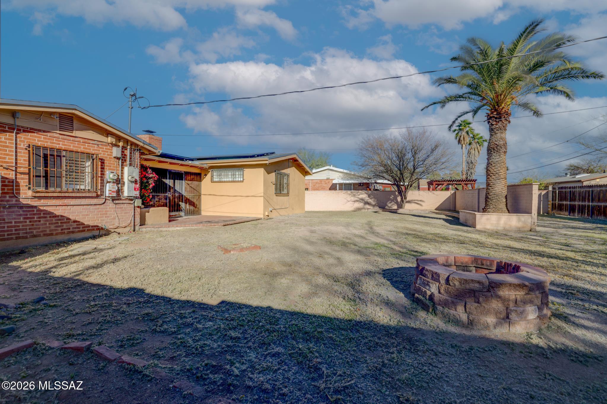 Inviting double-brick home in a central Tucson location filled with mid-century character, natural light, and a welcoming neighborhood feel. The open living room features a cozy brick fireplace with a refurbished chimney and double glass doors leading to an enclosed patio and spacious backyard designed for entertaining. Oversized lot offers room for RV/boat storage, a pool, or your dream outdoor retreat with no HOA. Bright kitchen includes ample cabinet space, pantry/utility room, veggie sink, and dishwasher. Flexible bonus space is perfect for a home office, gym, or hobby room. Recent upgrades include a new roof, solar power, new AC/heater, updated 3-prong electrical outlets, and refurbished bathroom. Primary suite features vaulted ceilings and a walk-in closet with built-ins.