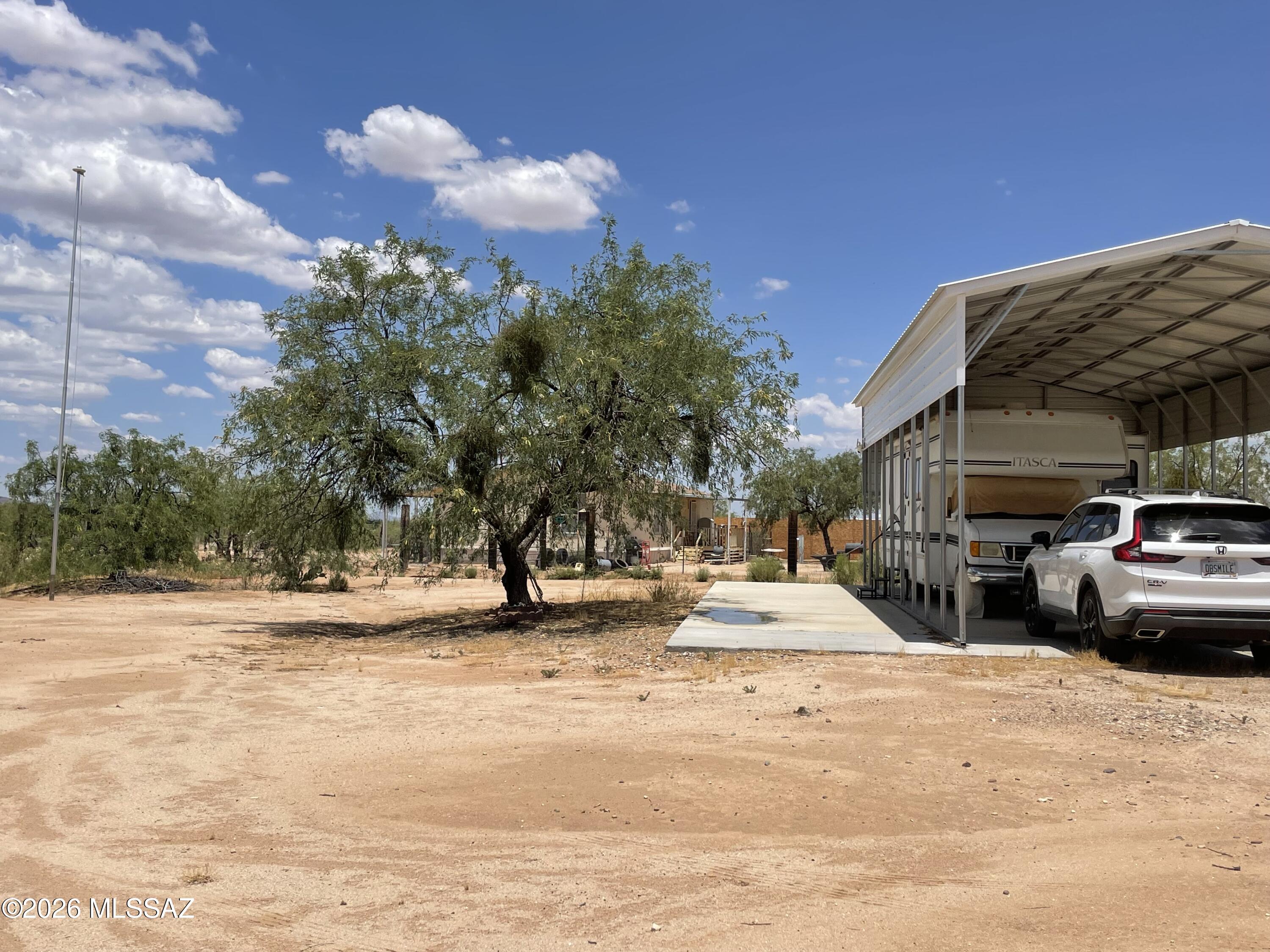 Enjoy the freedom and endless possibilities on this fully fenced one-acre property with no HOA! A versatile building & City of Tucson water with Trico electric is currently used as a workshop, laundry room, and extra storage. The impressive 40' x 50' slab & covered RV port offers plenty of room for RVs, vehicles, equipment, and projects, complete with 30- and 50-amp electric service and a septic system with hookups.  There's plenty of space to build your dream home, keep horses and pets, create a garden, or bring all your recreational toys. Enjoy breathtaking mountain and Kitt Peak views, unforgettable Arizona sunsets, & brilliant star-filled skies.