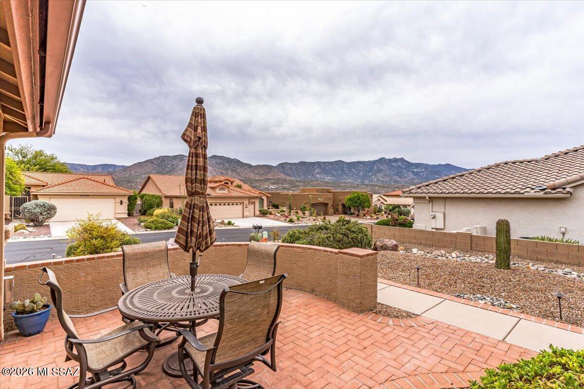 Positioned on an elevated corner lot within SaddleBrooke, this home pairs mountain views, thoughtful living spaces, and access to one of Southern Arizona's most active 55+ communities.
Designed with both comfort and flexibility in mind, the home features a split-bedroom floor plan with an additional den/bonus room, suited for hobbies, guests, or a home office. Inside, the aesthetic balances a classic Southwest exterior with a clean, tasteful interior, complemented by high ceilings, neutral finishes, and an interior laundry room.
The kitchen is arranged for both daily living and entertaining, offering stainless steel appliances, a breakfast bar, center island, and ample workspace. The adjacent living areas connect naturally to the outdoors, where an expansive covered porch captures mountain views and native desert plantings.
The primary suite includes a bay window seating area, oversized walk-in closet, dual-sink vanity, private toilet room, and a spacious layout designed with long-term comfort in mind.
Residents of SaddleBrooke enjoy access to an extensive collection of amenities and social opportunities, including golf, pickleball, fitness facilities, clubhouse activities, dining, and walking paths, creating a lifestyle centered around connection, recreation, and ease of living.
With its elevated setting, practical floor plan, and access to exceptional community amenities, this home offers an inviting opportunity within one of Oro Valley's most established active adult communities.