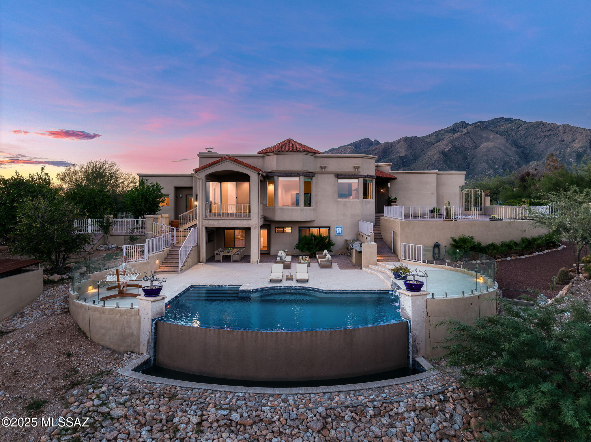 Commanding panoramic mountain, city, and desert views from every room and patio, this exceptional residence offers a seamless blend of privacy, scale, and resort-style living within Cimarron Foothills Estates, one of Tucson's most coveted enclaves in the Catalina Foothills. Perfectly positioned on a premium 1.27-acre ridge lot, the home captures the essence of elevated desert living at its finest.

The home's outdoor living experience is extraordinary, showcasing four distinct patios—north, south, east, and west—each capturing 360-degree views of the surrounding mountains, city lights, and desert landscape. The redesigned south patio and newer pool evoke a resort atmosphere with spa jets, a custom retaining wall, and new paver terraces for seamless indoor-outdoor entertaining. An outdoor built-in BBQ, finished with exotic blue-marble countertops, hot-and-cold-water sink, and custom lighting, elevates al fresco gatherings and celebrates the best of the Arizona lifestyle. The exterior also features 16 fruit trees, lush real grass, and three covered terraces, creating both beauty and function within the natural desert surroundings.

Inside, more than 3,800 square feet of refined living space are designed to celebrate the views from every vantage. The spacious great-room layout encompasses formal living and dining areas, a family room, and an open eat-in kitchen with breakfast bar and nook, offering effortless flow for entertaining or everyday living. The residence features four bedrooms plus a dedicated office / den or potential fifth bedroom, providing exceptional flexibility for guests, work, or multigenerational living.

The main level includes the primary suite, a guest suite with adjacent bath, the office / den, and a laundry room, allowing for comfortable main-level living while maintaining separation and flow. The lower level hosts two additional guest suites and a full bath, offering privacy and comfort for family or visitors. The home features new flooring throughout, a reimagined kitchen with updated cabinetry, countertops, and appliances. It also features picture windows that frame the surrounding landscape. The primary suite enjoys direct patio access and a spa-style bath with soaking tub and walk-in shower.

Nestled in the prestigious Catalina Foothills, residents of Cimarron Foothills Estates enjoy proximity to world-class golf, hiking in Sabino Canyon, and luxury shopping and dining at La Encantada, all just minutes away. The property lies within the highly rated Catalina Foothills School District (District 16).

Upgrades (over $300K) and notable features list available under documents. 

Schedule your private showing today!