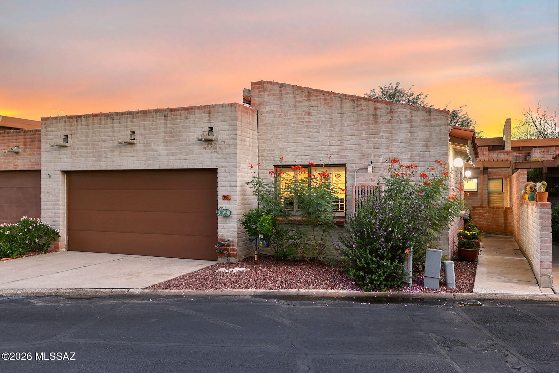 Ideally located near shopping, restaurants, the University of Arizona and UMC, this inviting home is tucked within a quaint community featuring authentic burnt adobe construction, a community pool, tennis courts and abundant guest parking. Inside, soaring ceilings, beamed details, natural Saltillo tile and skylights create warmth, character and an abundance of natural light. The beautifully upgraded kitchen is perfect for the home chef, with custom cabinetry, generous counter space, two hanging pot racks, double ovens and an electric cooktop. The flexible floor plan offers inviting spaces for both quiet relaxation and entertaining, including a dining area, casual eating space and a living room with a warm fireplace and an extended window seat. The spacious primary suite features a luxurious soaking tub, dual vanities and walk-in closet, while two guest bedrooms are thoughtfully separated for privacy. A private backyard showcases a distinctive distressed metal wall with custom etching, along with a covered patio for outdoor enjoyment. A spacious two-car garage completes this exceptional home.