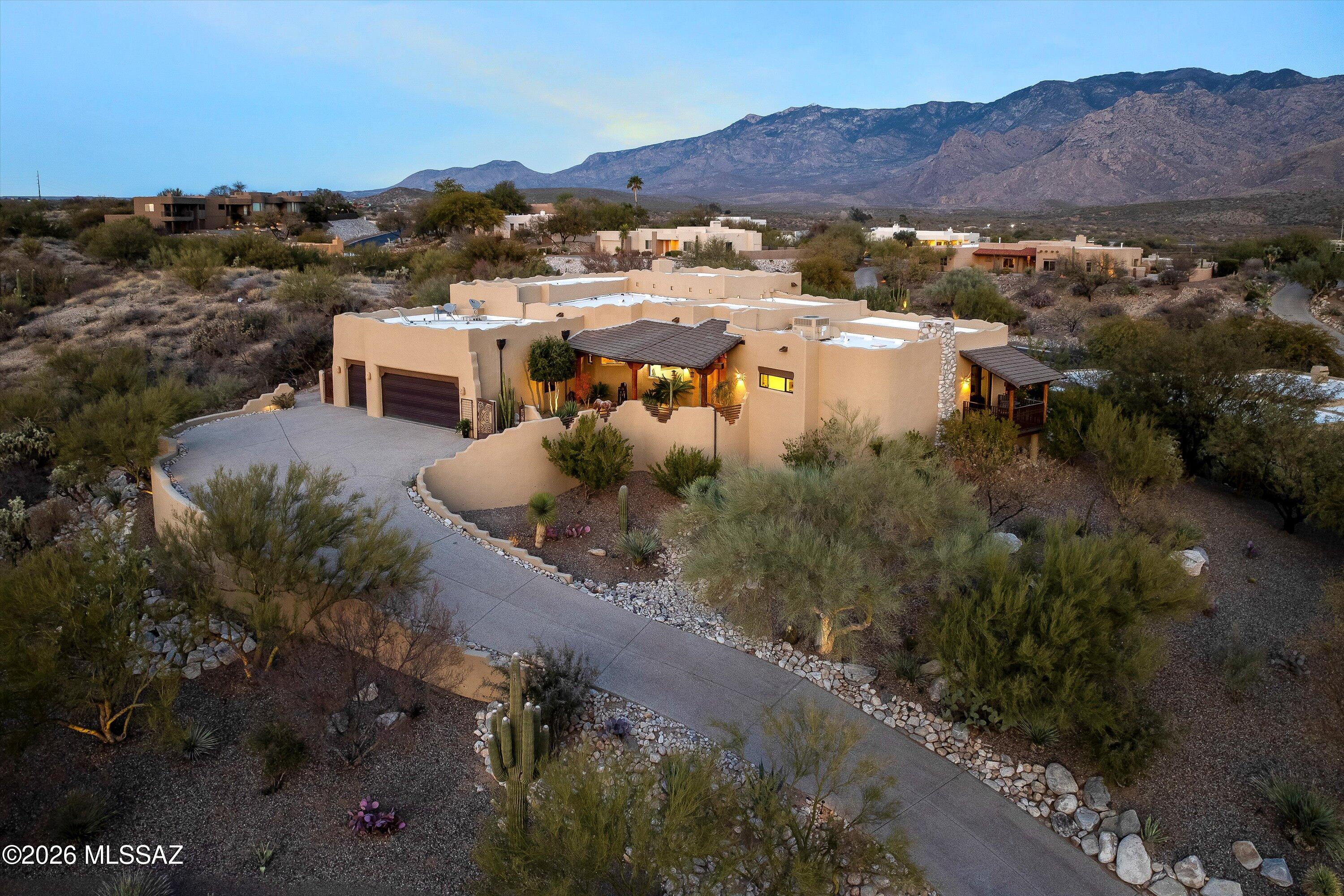 Experience timeless Southwestern elegance in this exceptional John Dolan-built Santa Fe residence, located within the prestigious gated community of Palisades Point in Oro Valley. Offering 3 bedrooms, 2.5 bathrooms, and approximately 3,150 square feet of refined living space, this home showcases breathtaking 180-degree views of the Pusch Ridge Mountains from nearly every angle. A stunning private courtyard entry sets the tone, welcoming you into a dramatic interior highlighted by soaring ceilings with authentic vega beams, saguaro rib ceilings, custom corbels, and walls of glass framing the unforgettable mountain backdrop. The expansive great room is anchored by a gas beehive fireplace and opens seamlessly to the patio, perfect for indoor-outdoor living and entertaining. A Separate dining room captures the same awe-inspiring views, creating an elegant setting for memorable gatherings. The gourmet kitchen is a chef's dream, featuring abundant granite and concrete countertops, custom cabinetry, and high-end appliances, including a built-in Miele espresso machine for the ultimate morning ritual. Home features a Aquasana whole-house water filtration system. The owner's suite is a true private retreat, offering a spa-like atmosphere with its own gas beehive fireplace and a private balcony to enjoy sunrise moments and sweeping mountain vistas. The luxurious ensuite bath includes dual vanities, a soaking jacuzzi tub, a walk-in shower with heated floor, and a custom-designed walk-in closet. A thoughtfully designed split floor plan provides added privacy for guests, with two spacious guest bedrooms connected by a well-appointed Jack-and-Jill bathroom. Step outside to a resort-style backyard designed to maximize the stunning surroundings. Enjoy a covered patio, multiple entertaining areas, and a cozy fire pit, each space intentionally positioned to take in the incredible views and serene desert beauty. Ideally located near premier dining, shopping, hiking and biking trails, golf, and all that Oro Valley has to offer, this home delivers luxury living as its finest in one of the area's most sought-after communities.