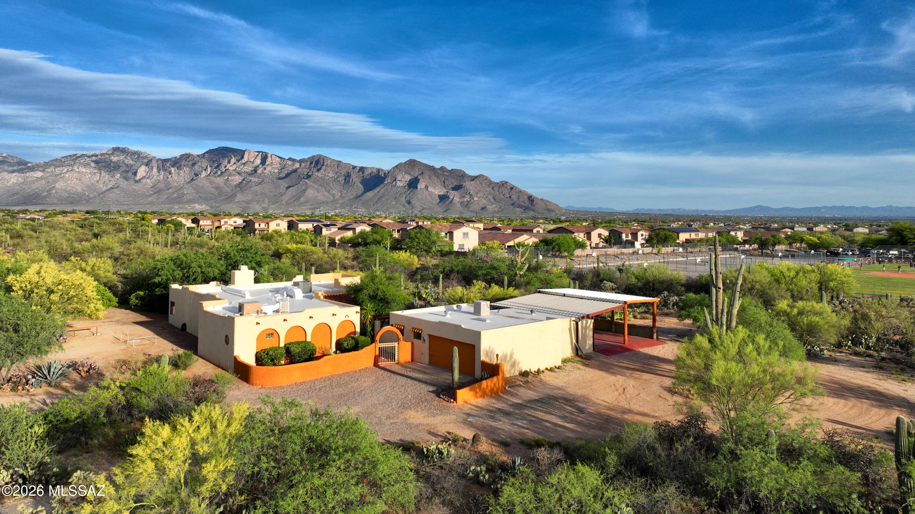 Experience the beauty of the Sonoran Desert in this charming Santa Fe-style hacienda with breathtaking 360-degree mountain views of Pusch Ridge, the Catalina Mountains, and the Tortolita Mountains. This 3-bedroom, 2-bath home includes a separate en-suite guest quarters, ideal for visitors or multi-generational living.

The open-concept great room features a striking rock wood-burning fireplace, expansive breakfast bar, and serene desert views. The updated kitchen offers tiled countertops, stainless steel energy-efficient appliances, and a large picture window showcasing the desert in motion. Tile flooring runs throughout, with wood laminate in bedrooms two and three, while dual HVAC systems provide year-round comfort. Don't forget to check out the video and the rest of the description. The spacious owner's suite includes dual sinks, a walk-in snail shower, separate jetted jacuzzi tub, and a generous walk-in closet.
Enjoy outdoor living with a covered wraparound porch and a separate BBQ and outdoor kitchen area, perfect for entertaining. Take in stunning sunrises and vibrant desert sunsets from your private retreat.
Additional features include a detached 2-car garage, spacious workshop, office or den, and extra storage (not included in square footage) with potential to convert into a private casita. A metal carport accommodates two RVs with 30/50 amp hookups or up to four vehicles.
Set on 4.29 saguaro-studded acres, this equestrian-friendly property offers space, privacy, and natural beauty. Located near the Oro Valley multi-use path, The Loop, Catalina State Park, Wilson K-8, golf, I-10, and shopping.