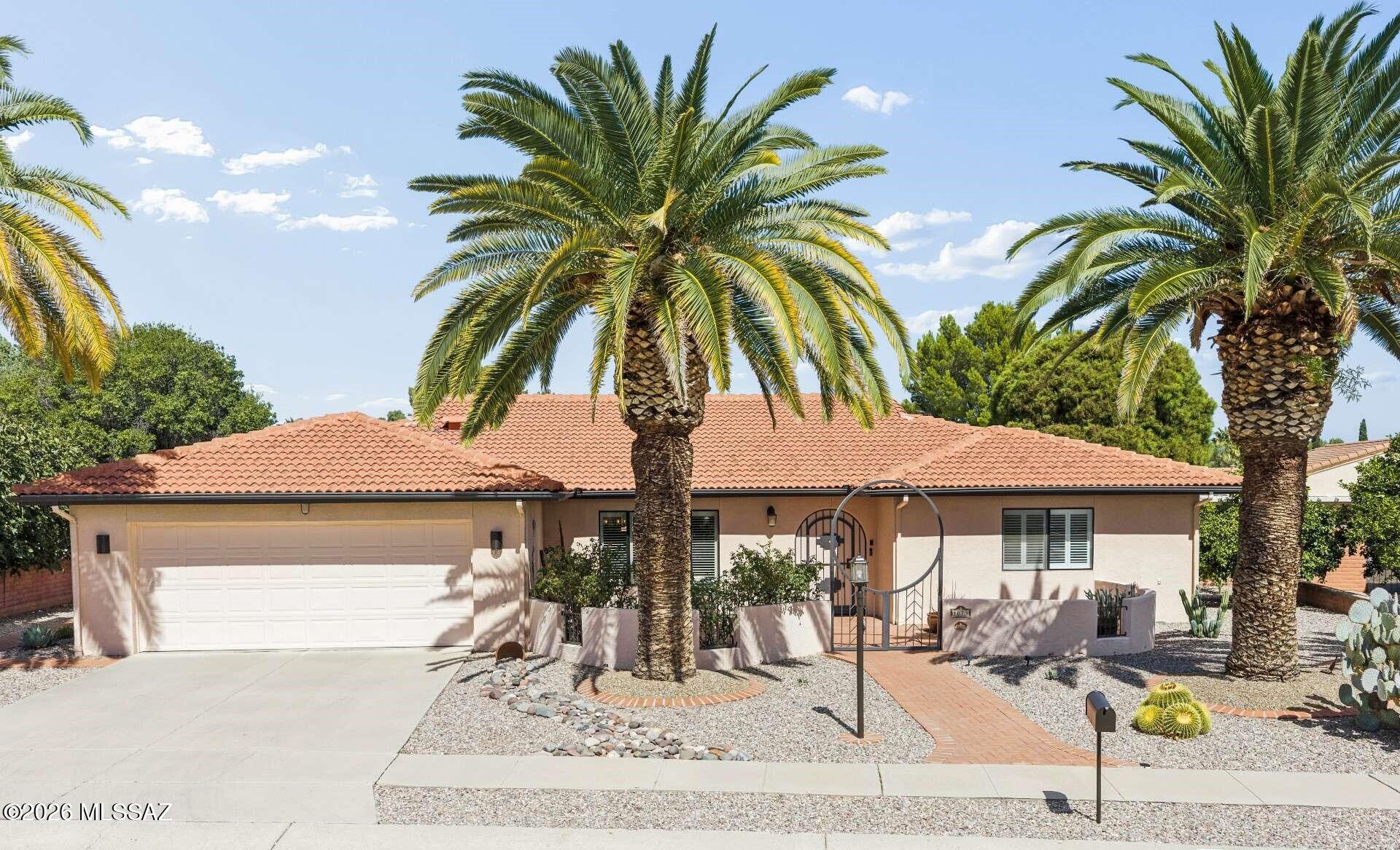 This distinguished retirement opportunity in Southern Arizona features a meticulously designed, custom-built residence with impressive curb appeal, including a tile roof, stately palm trees, and a distinctive metal gate opening to a private courtyard. The inviting entryway features an exquisite leaded-glass front door, setting an elegant tone from the outset.  The spacious interior features neutral tile flooring throughout, accommodating a variety of decorative styles while making maintenance easy. The chef's kitchen is a true showstopper with rich knotty alder cabinetry, elegant quartz countertops, and a striking mosaic glass backsplash. This well-appointed kitchen appeals to culinary enthusiasts and supports entertaining with its open layout and pre-plumbing for gas appliances.  Enjoy a tranquil primary suite with wood-look tile flooring and an ensuite bath featuring a dual-sink vanity and a custom tiled shower. With three oversized bedrooms and a versatile den or family room, there's plenty of room for hobbies, visiting guests, or simply relaxing in style. The exterior features an expansive, covered, tiled patio, creating an exquisite backyard oasis thoughtfully landscaped by a professional gardener. The privacy hedge and multiple entertaining areas make it perfect for enjoying Arizona's beautiful weather year-round. With minimal annual HOA dues, Green Valley Recreation membership, and a fantastic central location, this exceptional home is a unique opportunity.  Embrace retirement living at its finest--don't miss this wonderful opportunity to make it yours!