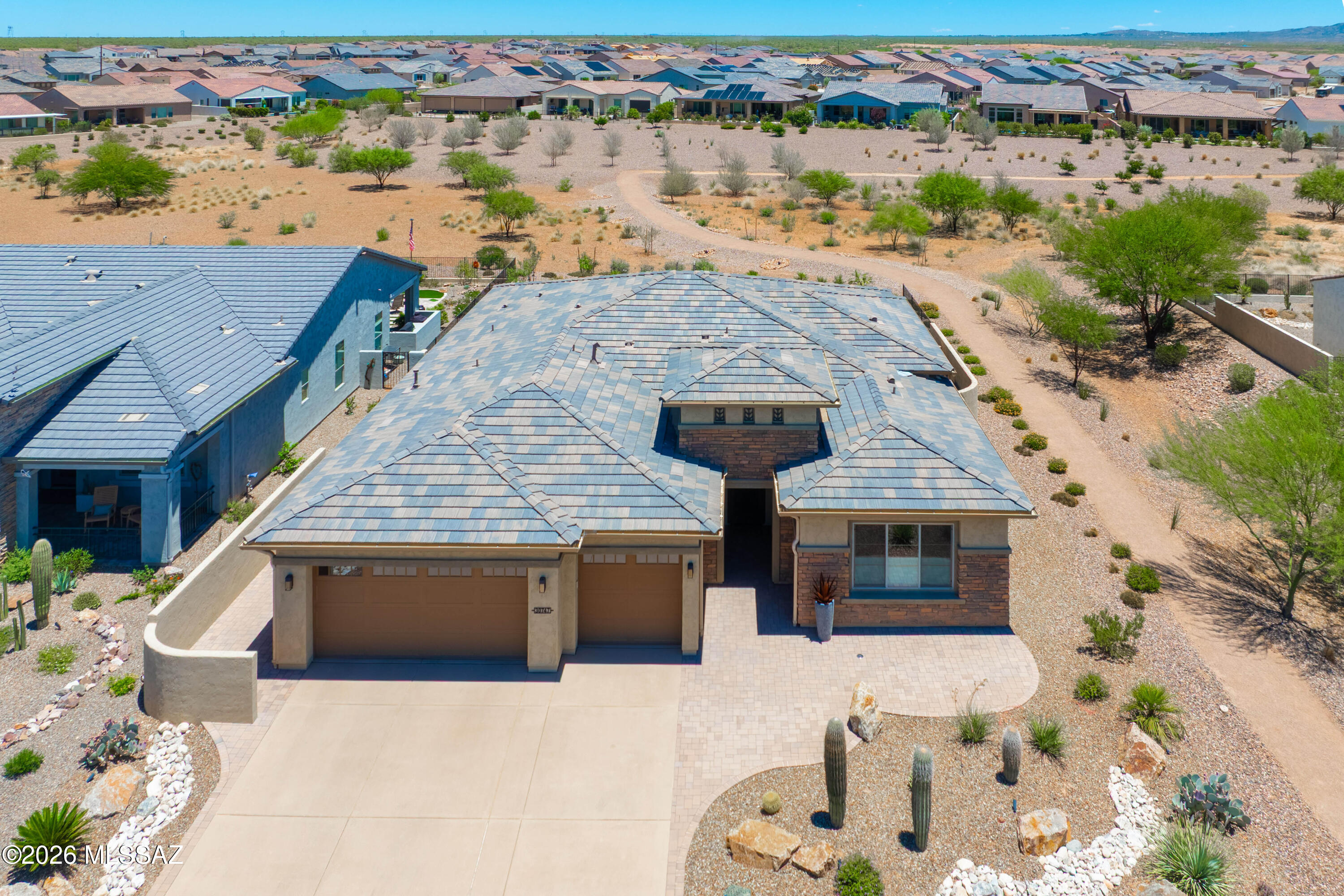 Turn key Vienta Model on a premium lot with stunning Tortolita and Catalina Mountain views! Set back an additional 5 feet from the street, this home impresses from arrival with a paver entry, iron security door, and epoxied driveway. Inside, luxury vinyl plank flooring, tall doors, and upgraded trim flow through a gourmet kitchen featuring quartz countertops, designer backsplash, farmhouse sink, upgraded cabinetry, and a wet bar with wine refrigerator. The primary suite is a true retreat with crown molding, a soaking tub, walk-in tile shower, makeup vanity, and Hunter Douglas motorized blinds. Guests enjoy an expanded bedroom and upgraded bath. A den with doors, laundry room with abundant cabinetry and sink, whole-home water filtration, and an extensively upgraded garage with epoxy floors, custom cabinets, extra lighting, and side-yard access complete the package. Outside, a built-in BBQ with refrigerator and storage, electric patio shades, and covered patio TV overlook a natural arroyo, walking trails, and breathtaking mountain views. Flat screen TVs and a whole-home Sonos sound system are negotiable with the sale -- originally purchased for $11,000.