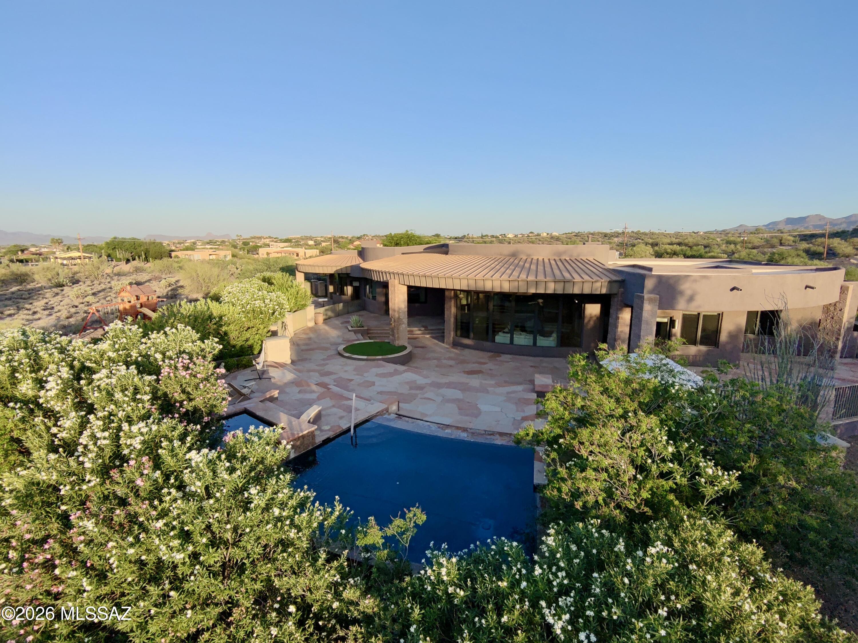 Designed by renowned architect Marc Soloway, this exceptional residence sits on 3.3 acres of rare, flat, fully usable land in the heart of Oro Valley.Solid masonry construction offers durability and timeless appeal.Walls of windows frame breathtaking views of Pusch Ridge, the Catalina Mountains,city lights & spectacular Arizona sunsets. Soloway's signature curved design creates a seamless flow between living spaces while blending indoor and outdoor living. The thoughtful split floorplan provides privacy for owners and guests alike. Enjoy 2,208 sq ft of covered patio space, expansive flagstone patios, a resort-style grotto pool, heated spa with cascading waterfalls, mature landscaping, and exceptional privacy. Multiuse path access to Naranja Park, trails, library, schools, dining & shopping Beyond the architecture, the true rarity of this estate is the land itself. Flat, fully usable acreage of this size is increasingly difficult to find in Oro Valley, where many luxury homes are built on steep or heavily terraced lots. Here, the grounds function as an extension of the residence, creating a private compound surrounded by mature landscaping, flowering oleanders, and dramatic outdoor living spaces.

Walls of glass blur the line between indoors and outdoors, filling the home with natural light and framing views in every direction. The covered patios and expansive flagstone terraces invite year-round entertaining, quiet mornings watching the sunrise over the Catalinas, and evenings spent enjoying the city lights and the soothing sound of cascading water from the spa and pool.

Ideally situated across from Naranja Park and connected by a new multiuse path, the property offers convenient access to trails, recreation, the Oro Valley Library, dining, and shopping while maintaining a sense of privacy rarely found in such a central location. Combining renowned architecture, solid masonry construction, mature grounds, and a truly irreplaceable homesite, this residence represents a rare opportunity in the Oro Valley luxury market.