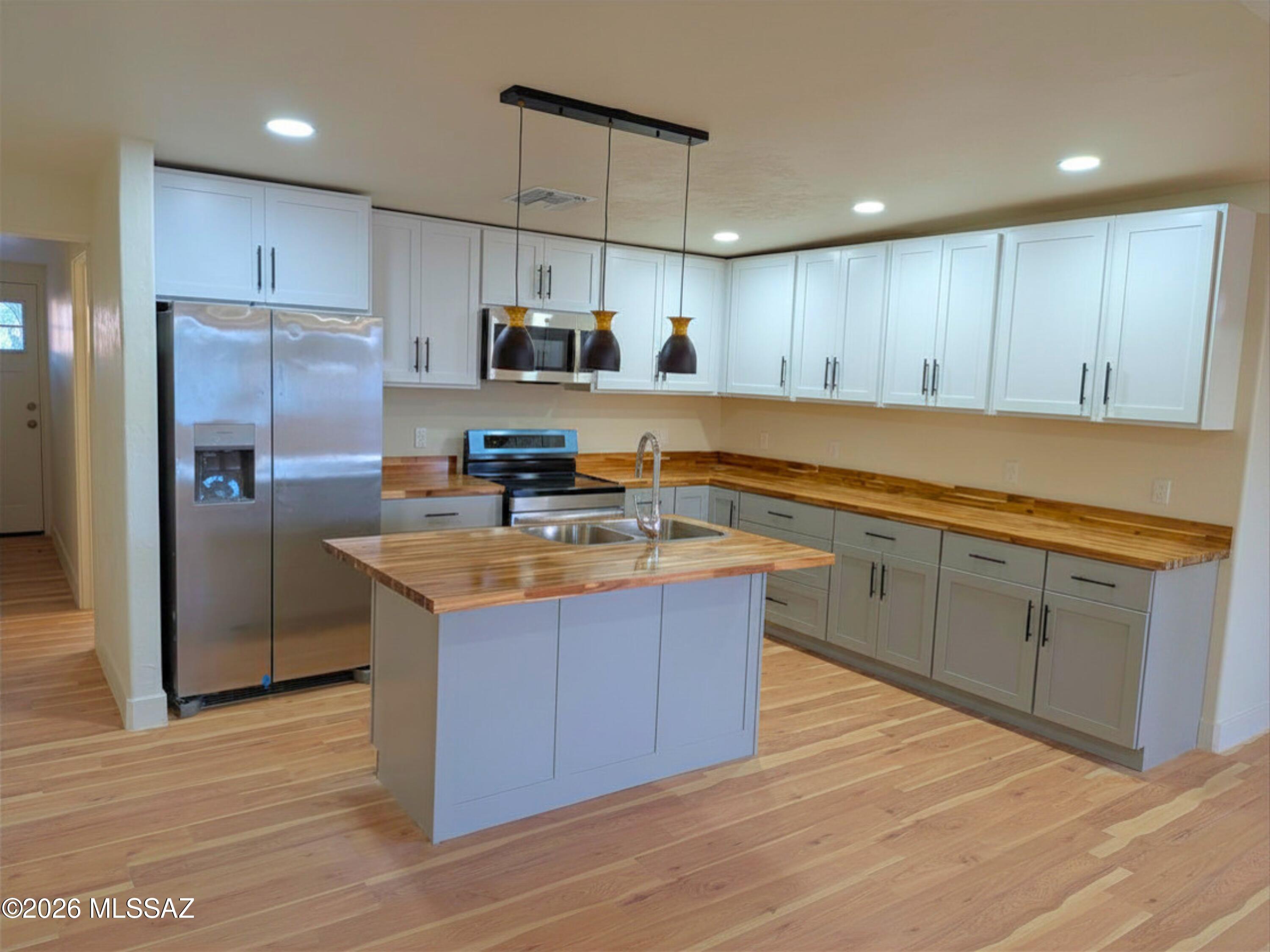 If you've been watching the 85706 market, you know it's nearly impossible to find a true 3-bedroom townhome with this footprint (1,245 sq ft) that doesn't require a contractor on day one. 4937 S Cherry Ave is the exception. This isn't a quick cosmetic touch-up; it is a top-to-bottom, permitted reimagining of the space, executing a modern aesthetic rarely seen at this price point.

From the curb, the smooth white stucco, black trim, and custom metal fencing set an immediate modern tone. The rear courtyard features a zero-maintenance architectural concrete and artificial turf grid, secured by a rolling metal gate--perfect for private outdoor living or secure parking.

Inside, continuous light wood-plank flooring runs through an open-concept floor plan flooded with natural light. The kitc
