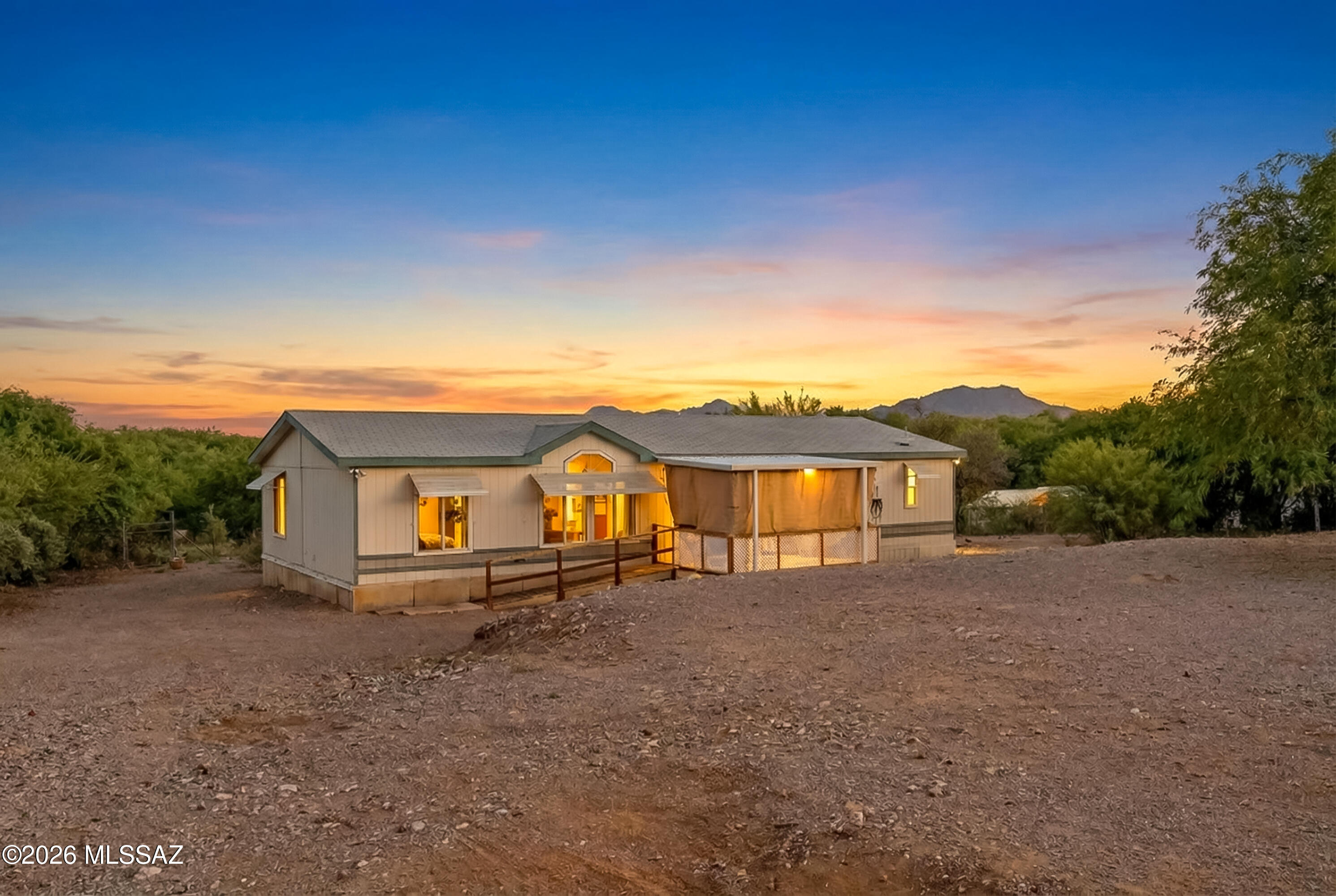 Discover peaceful desert living with space, privacy, and endless potential. Nestled on 1.1 
acres and set back from the road, this well-maintained property offers a quiet setting 
surrounded by natural beauty.
 
This light and inviting 3-bedroom, 2-bath home welcomes you with an open great room and kitchen concept, enhanced by picture windows, elevated ceilings, and inset lighting that  create a bright, airy feel throughout. The layout is thoughtfully designed, with the spacious 
owner's suite tucked to one side, featuring a private bath and an extended bonus room that  is perfect for a home office, hobby space, or quiet retreat. On the opposite side, two  additional bedrooms and a full bath provide comfort and flexibility. 

Enjoy Arizona's stunning sunrises and - sunsets from your front screened-in porch or the 
expansive back deck, offering plenty of space to relax or entertain. The home features laminate flooring throughout, has been well cared for, and includes all appliances, including a newer refrigerator. A ramp provides added accessibility and ease of entry.
 
Approximately half of the acreage is fenced, while the back portion opens to a beautiful riparian area, creating a peaceful and unique natural setting. Per the seller, there may be an opportunity to place a second home on the property, offering additional flexibility for multigenerational living or future use. Buyers are encouraged to verify with Pima County. 

Conveniently located near a local mini market and with easy access to I-19, this property offers the perfect balance of rural charm and everyday convenience, with nearby access to 
Green Valley, Tubac, and Tucson. 

This is more than a home; it is space, versatility, and a lifestyle ready to be enjoyed.