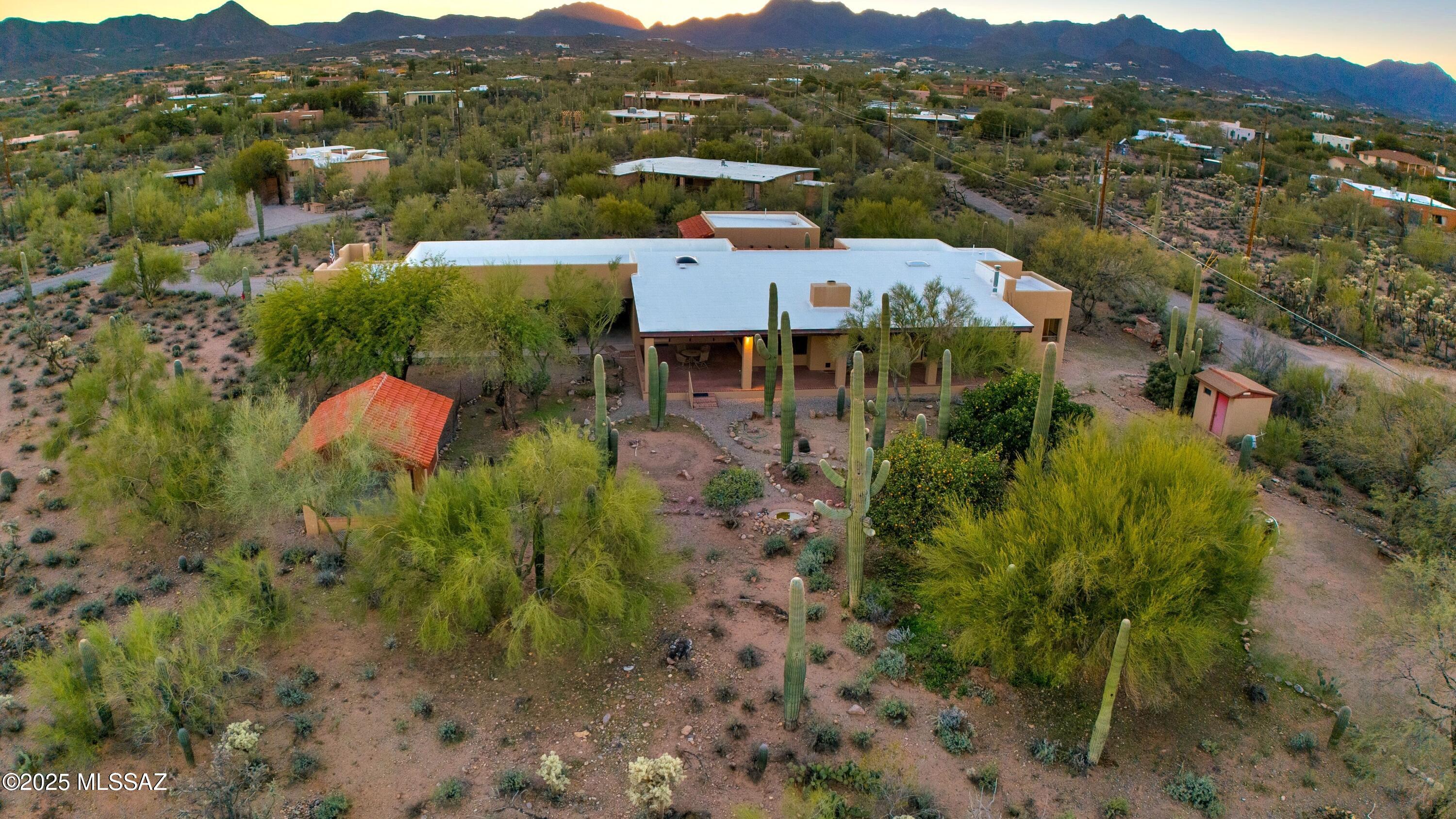 Discover comfort, versatility, and true desert serenity on this exceptional 1-acre Santa Fe-style estate, complete with a charming Guest House, a rare opportunity offering enhanced privacy, future resale flexibility, or an appealing long-term investment. With NO HOA, this property invites a lifestyle defined by freedom and connection to the natural landscape.

Custom-built by its original owner, renowned for impeccable craftsmanship and perfectionist standards, the home captures authentic Southwest character. High wood-beam ceilings, rich wood floors, and expansive windows create a bright, inviting interior anchored by a dramatic stone fireplace that sets the tone for relaxed desert living. The spacious bedrooms, along with a dedicated office featuring built-in bookshelves, offer comfort and thoughtful functionality for working or unwinding at home.

The separate Guest House is a standout feature, offering visitors or extended family their own private oasis with a full kitchen, living area, and bath an ideal blend of independence and connection to the main residence.

For hobbyists and creatives, the property includes a generous workshop equipped with water and electricity, perfect for automotive projects, woodworking, crafts, or storage. Outdoor living is just as impressive, with amenities designed for both enjoyment and exploration: a BBQ hut/ramada, a peaceful cement wildlife pond, dog run with water access, horseshoe pit, basketball hoop, and meandering walkways that encourage you to roam the grounds.

The expansive patio becomes the heart of everyday living and entertaining, capturing breathtaking mountain and city views while offering unmatched privacy. Whether relaxing quietly at sunset or hosting loved ones, this space embodies effortless desert living.
All of this is just minutes from local conveniences, hiking, downtown Tucson, Starr Pass, and the University of Arizona, offering the perfect balance of tranquility and accessibility.