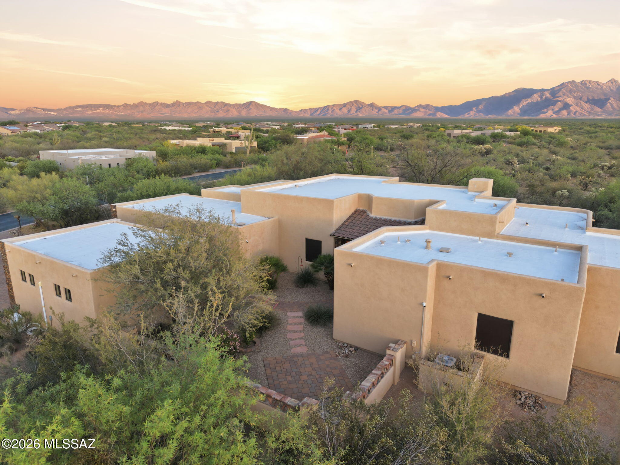 Set against a backdrop of sweeping desert & mountain views, this exceptional property offers the kind of space, privacy, & quiet beauty that defines true Arizona living. Tucked away on a generous homesite, the home unfolds with a seamless blend of indoor comfort and outdoor serenity--where mornings begin with soft desert light & evenings gather around the fire pit under wide open skies. A private front courtyard welcomes you in. Inside, the open-concept design creates an effortless flow between the living, dining, & kitchen areas, all anchored by expansive windows that frame the natural landscape beyond. The chef's kitchen features granite countertops & rich knotty alder cabinetry, carried throughout the home for a warm, cohesive feel. The formal dining area & family room are enhanced by a coffered ceiling, adding architectural depth and character. Polished travertine tile--professionally cleaned, sealed, and finished with refreshed grout--flows throughout the main living areas, paired with matching travertine baseboards. Throughout the home, 8-foot interior doors are framed with detailed wood trim and custom accent corner details, adding a refined architectural touch. The heart of the home is warm and inviting, designed for connection, whether hosting guests or enjoying a quiet night in. All four bedrooms offer comfort and retreat, enhanced by brand new lush carpeting that brings a fresh, luxurious feel underfoot. The primary suite is a true sanctuary--spacious and serene, with peaceful views and direct outdoor access, featuring a jetted soaking tub, makeup vanity, and elegant vessel sinks for a private retreat at day's end. Step outside and you'll find multiple covered patio spaces designed for year-round enjoyment, supported by striking stone columns and rich wood beams. The backyard offers a perfect balance of relaxation and recreation, with room to entertain, play, or simply soak in the surrounding beauty. Car enthusiasts will appreciate the rare 4-car garage setup with two separate 2-car garages, one of which is fully upgraded with an epoxy-coated floor, painted interior, and an 18K BTU mini-split system for heating and cooling--currently used as a home gym. Additional improvements bring peace of mind and efficiency, including a recoated roof (May 2023), new bug screens on all windows, solar screens on select west-facing windows, new exterior door seals, and a 5-year termite treatment completed in June 2024. This is more than just a home--it's a place where comfort meets craftsmanship, where every upgrade has been considered, and where the surrounding landscape becomes part of your everyday living experience.