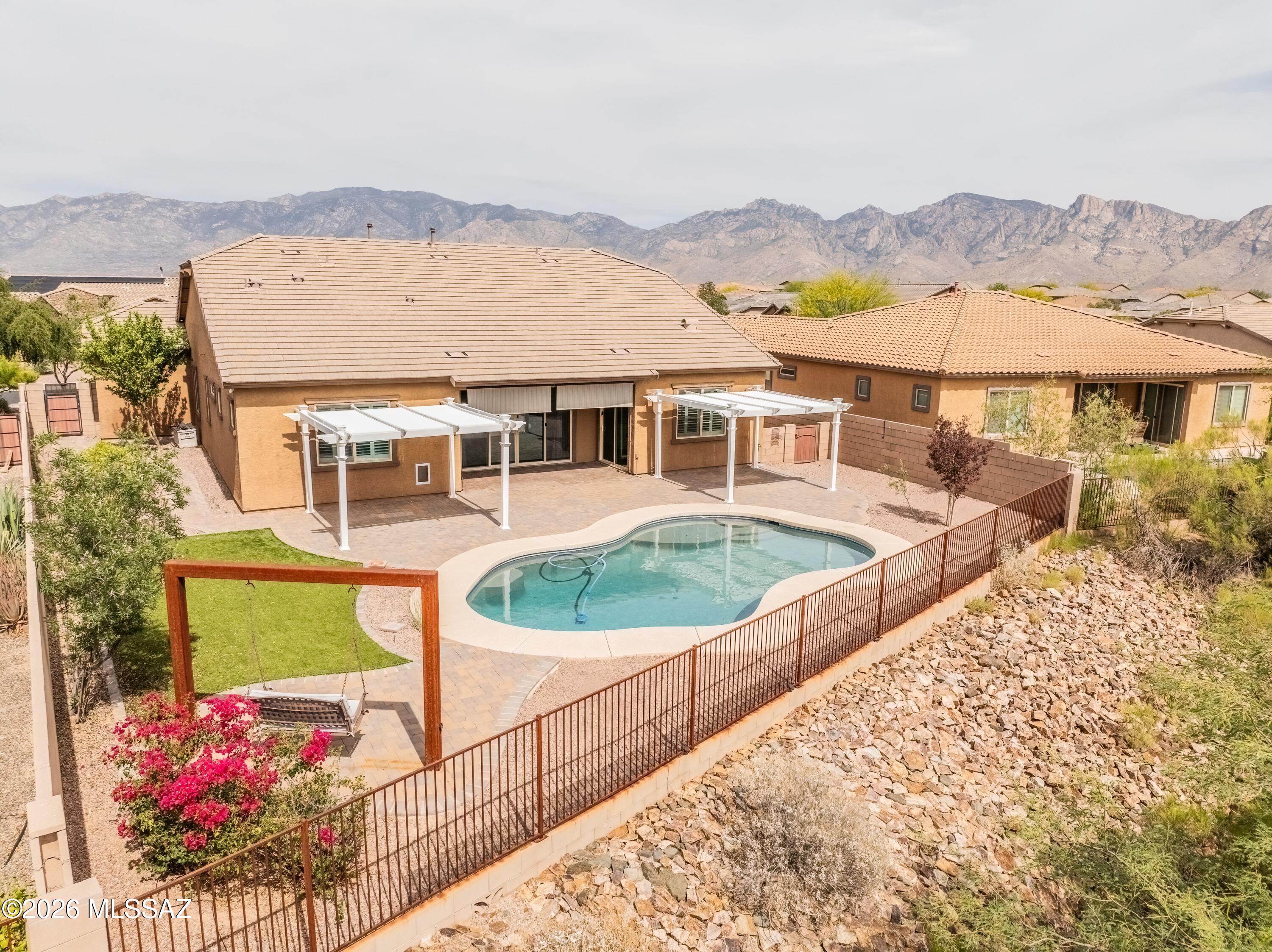 Amazing Oro Valley home with mountain views and unforgettable sunsets, this exceptional residence blends luxury, versatility and Fabulous Arizona living. From the moment you arrive through the custom iron-gated courtyard entrance, every detail of this home reflects elevated design and thoughtful craftsmanship. At the heart of the home is a stunning chef's kitchen designed to impress, featuring top-of-the-line Monogram appliances including a professional-grade range, oven, wine and beverage refrigerator, expansive walk-in pantry, and striking two-tone cabinetry with soft-close finishes. The oversized island anchors the space beautifully, while the open-concept great room is enhanced by a sleek modern fireplace and dramatic 12-foot sliding glass doors that seamlessly blend indoor and outdoor living. Venture outside to a true backyard retreat where resort-style living awaits. A sparkling pool, covered patio with plenty of lounge spaces, elegant paver hardscaping, and lush landscaping create the ultimate setting for entertaining or relaxing beneath Arizona's breathtaking sunsets. The expansive green space bordering the property enhances the sense of privacy while framing picturesque views of the Tortolita Mountains and Catalina vistas beyond. One of the home's most desirable features is the highly sought-after NextGen suite offering the flexibility of private entrance or interior access for a seamless extension of the home. Perfect for multigenerational living, guests, or a private retreat, this beautifully appointed space includes a spacious bedroom with walk-in closet, dedicated laundry area, full kitchenette with refrigerator, sink, dishwasher, and oven, along with direct access to a private patio showcasing Catalina Mountain views. And we can't forget the amazing 4-car garage for all your toys and added space. This remarkable Oro Valley home offers the perfect balance of elegance, comfort, privacy, and space, all with effortless desert living.