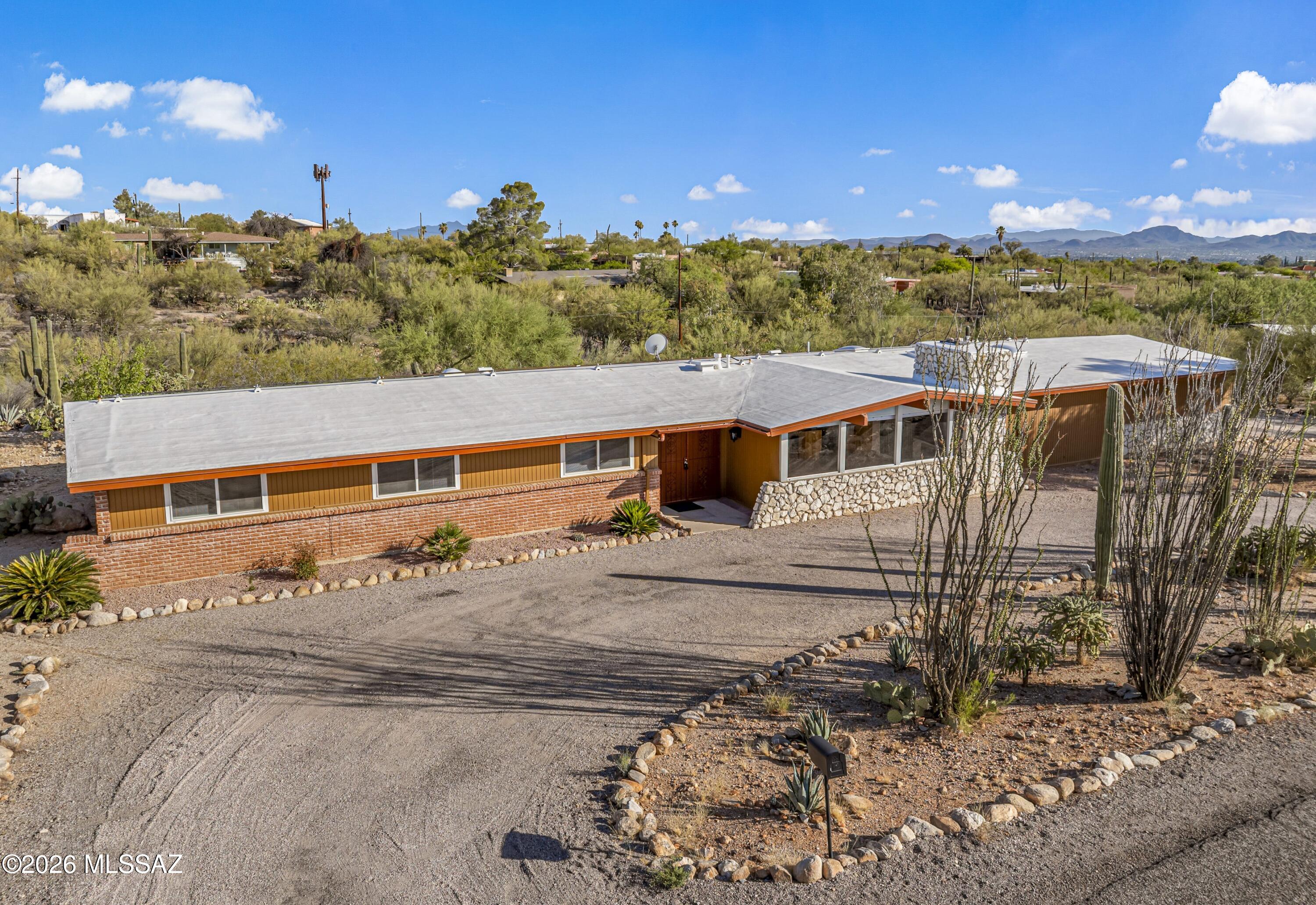 Classic mid-century modern home in an awesome foothills location with mountain views, timeless architecture, and endless potential. Double-door entry opens to vaulted ceilings, large picture windows, and a dramatic stone fireplace wall anchoring the living room while framing the views beyond. Kitchen features stainless steel appliances, granite counters, and large island with breakfast bar. Huge family room offers great entertaining space. Spacious primary suite with updated shower, 3 additional bedrooms, and full guest bath. Enormous covered patio overlooks a private walled backyard ready for your dream outdoor oasis. Circular driveway, 2-car garage, and close to shopping, dining, and more